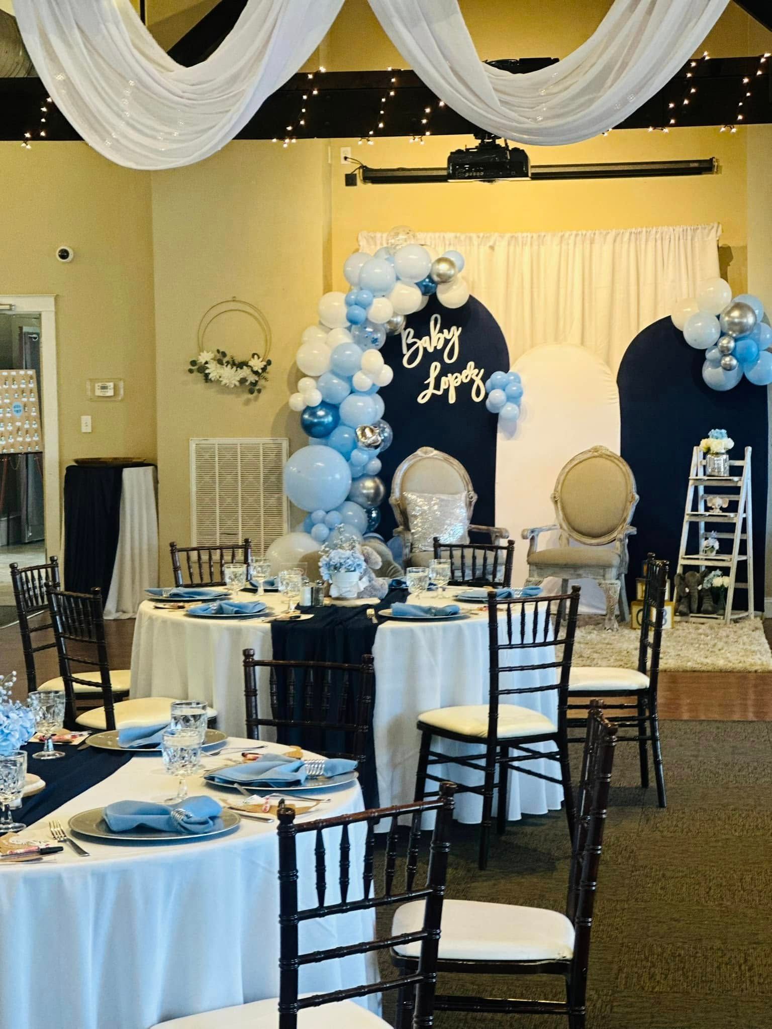 A room with tables and chairs set up for a baby shower.