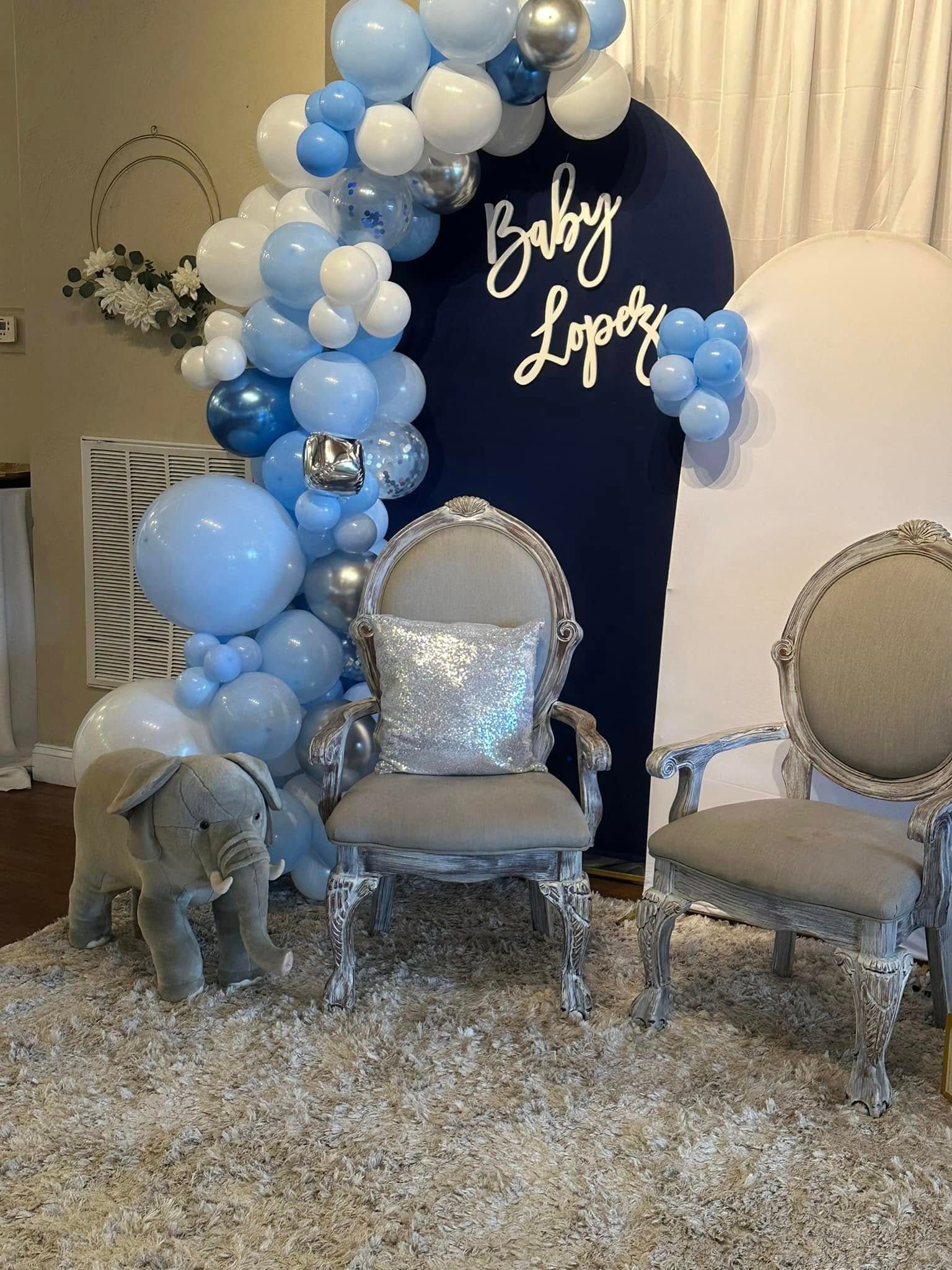 A room decorated with balloons , chairs , and a stuffed elephant.