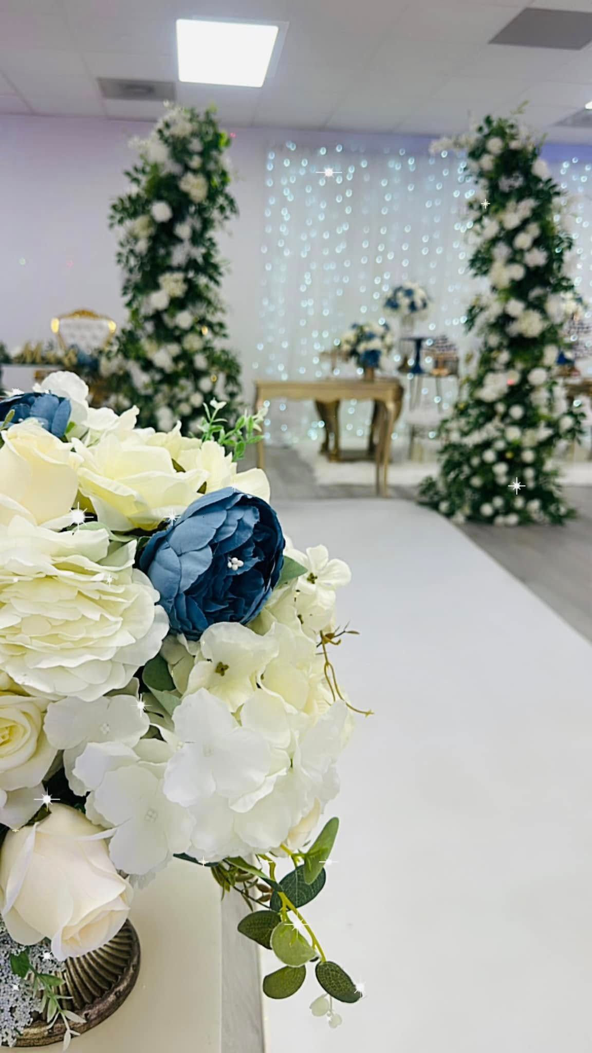 A vase filled with white and blue flowers is sitting on a table in a room.