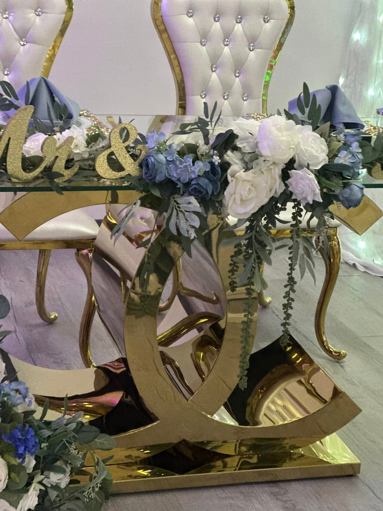 A glass table with flowers on it and a gold base.