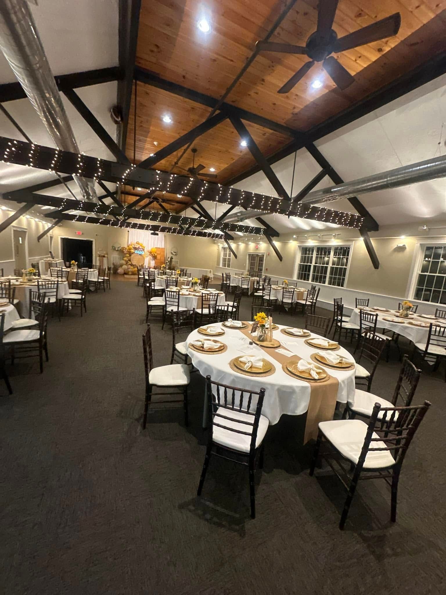 A large room with tables and chairs set up for a wedding reception.