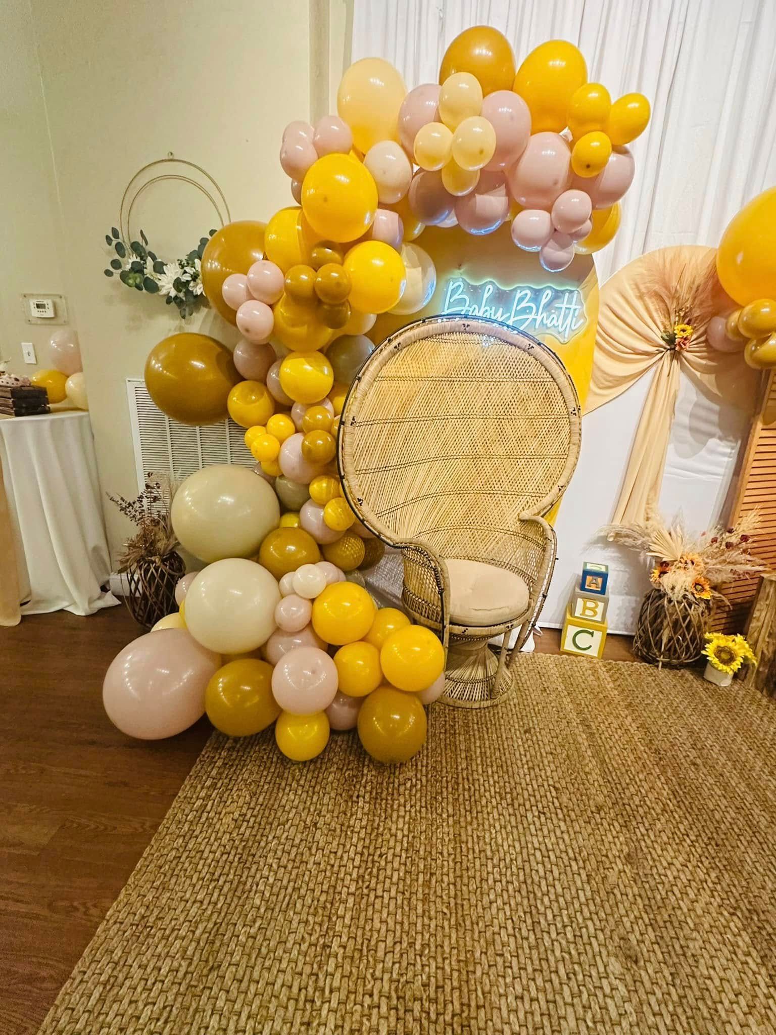 A wicker chair is surrounded by balloons in a room.