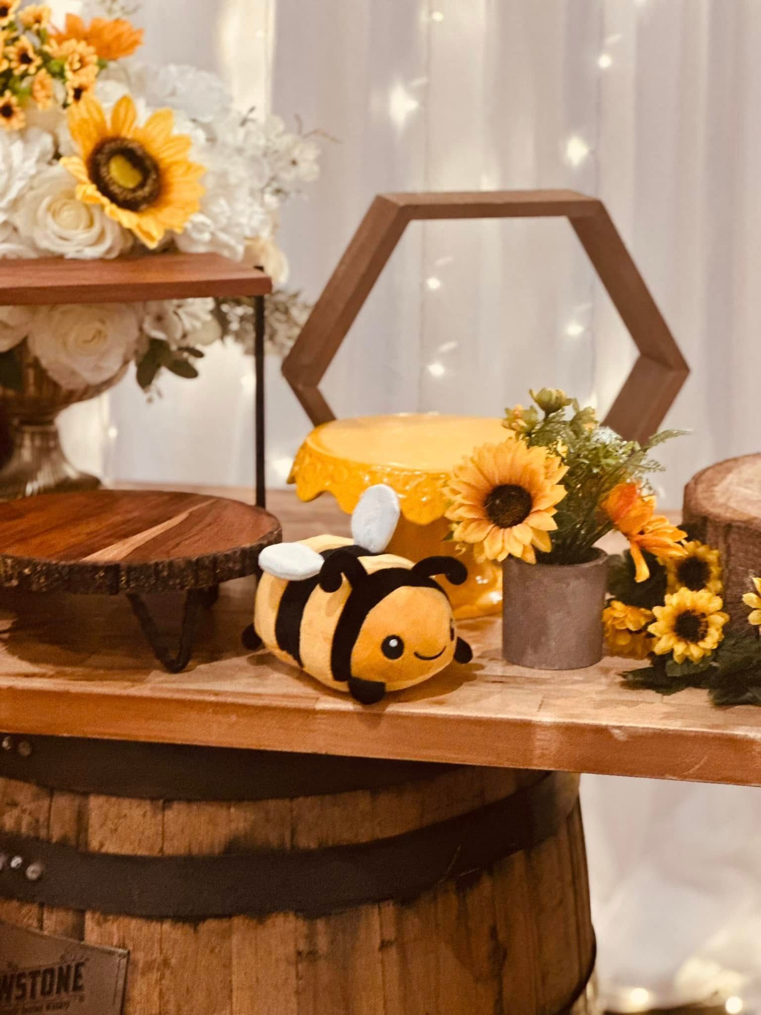 A stuffed bee is sitting on top of a wooden table.