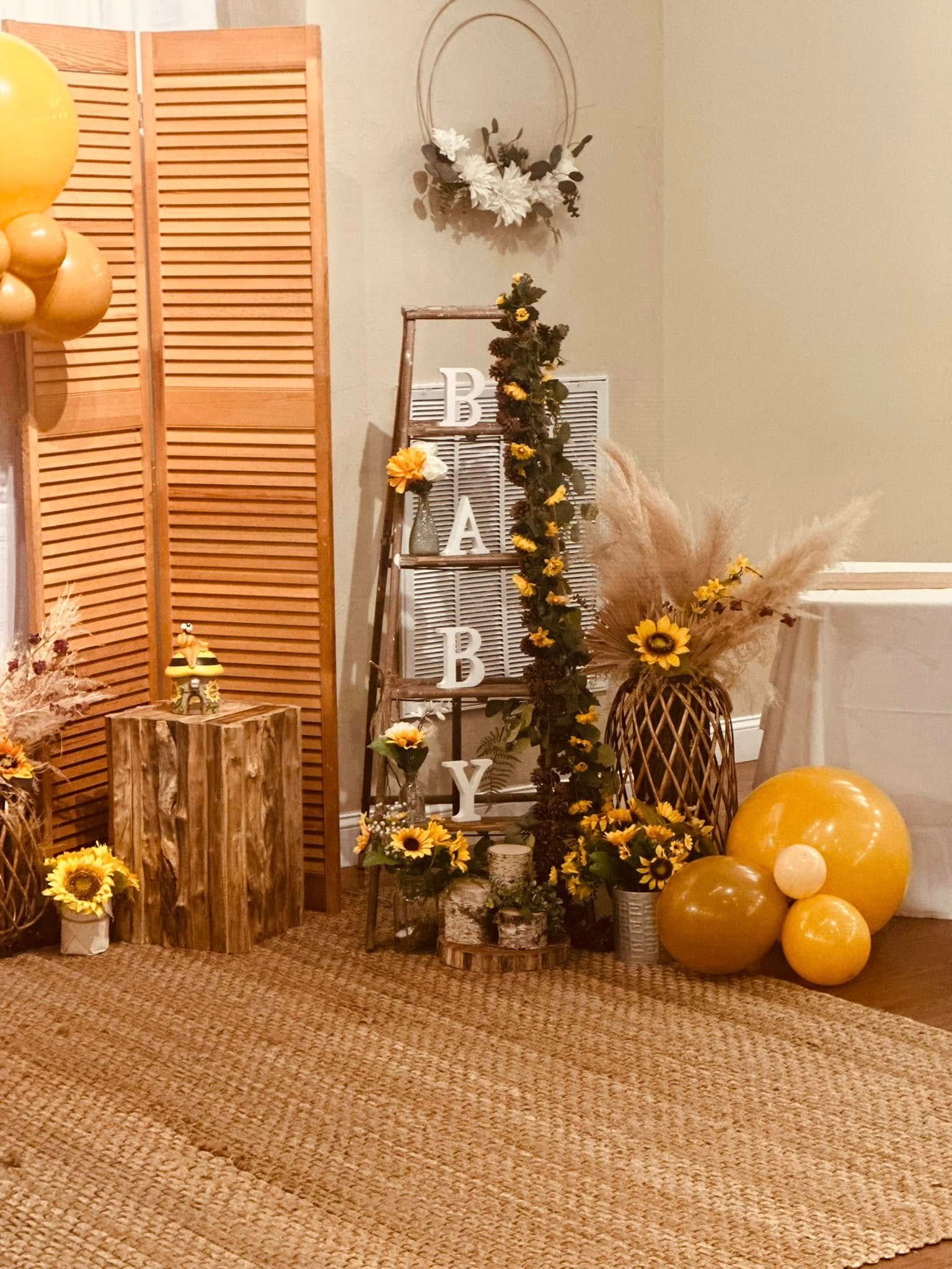 A room decorated with yellow balloons , flowers , and a ladder.