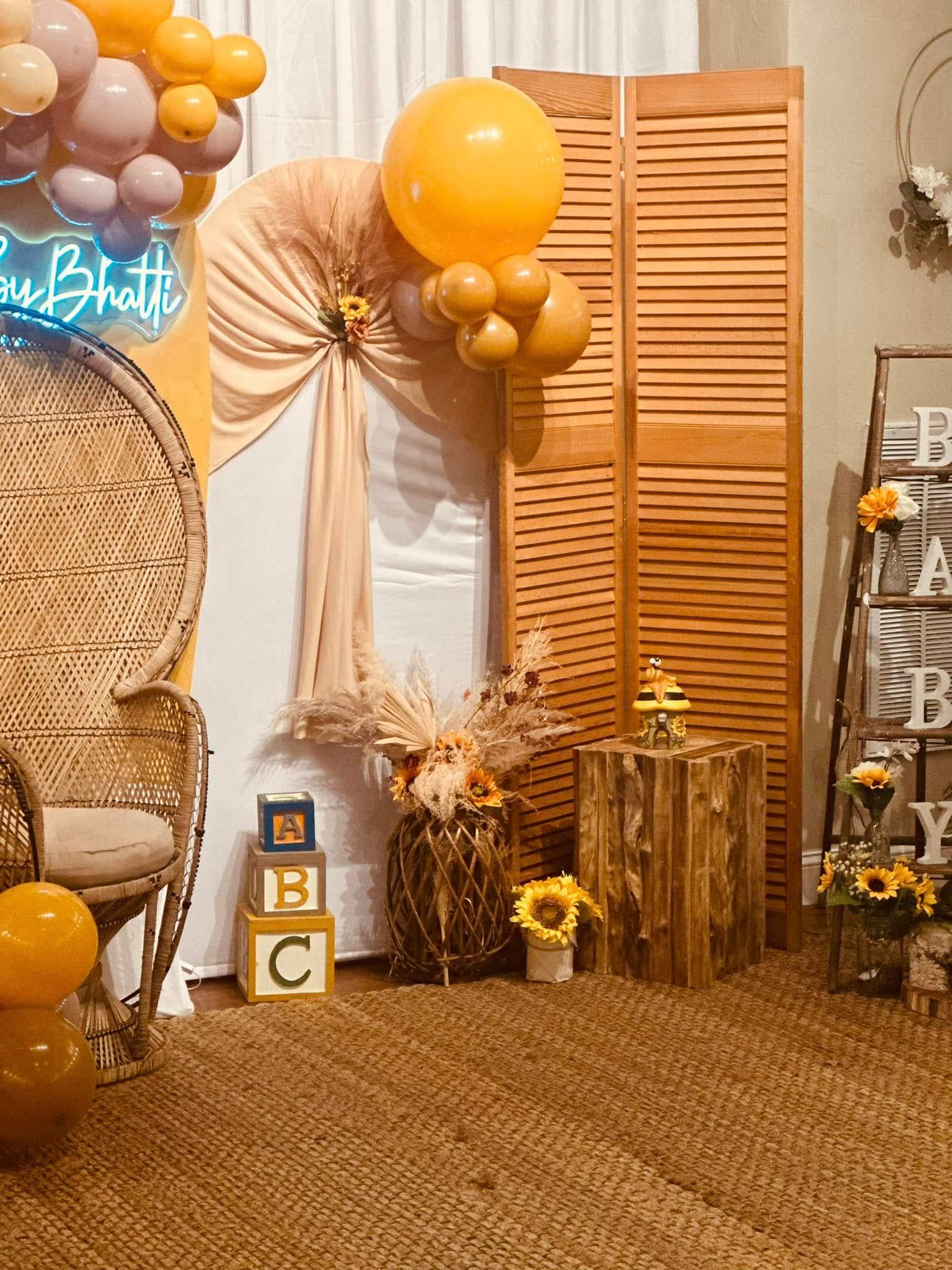 A room decorated with balloons , flowers , a peacock chair , and a ladder.