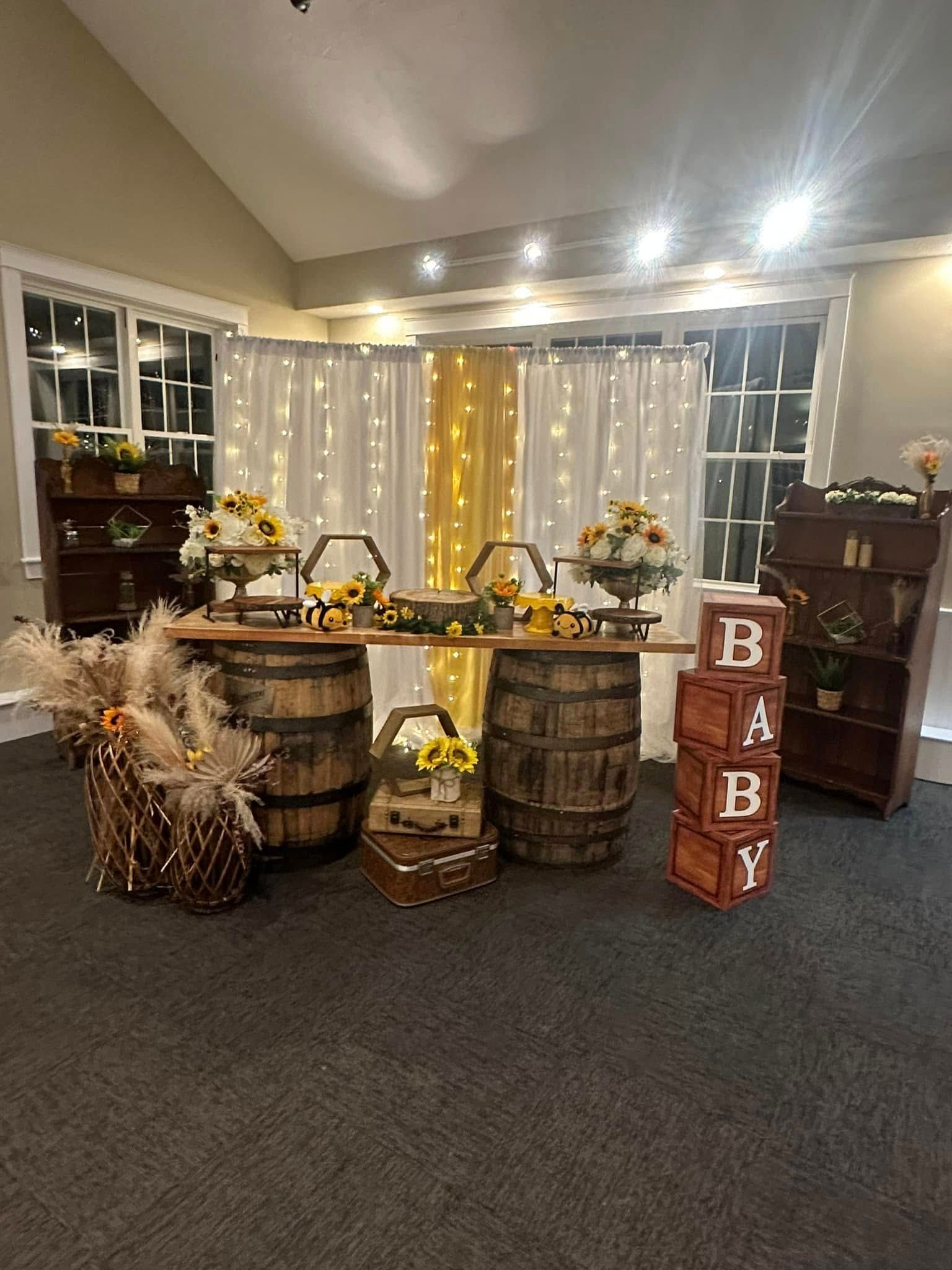 A room with a table and barrels decorated for a baby shower.