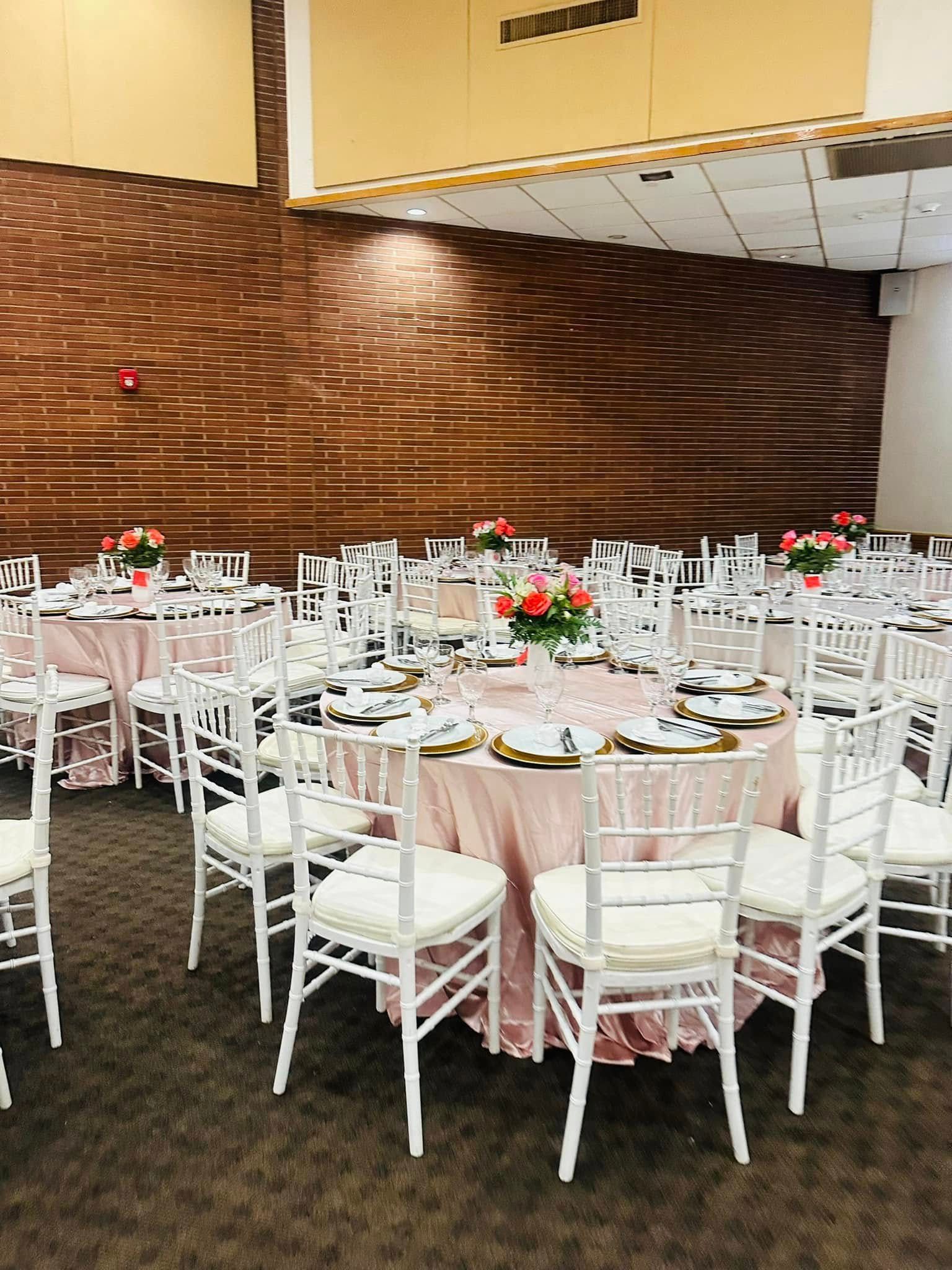 A large room with tables and chairs set up for a wedding reception.