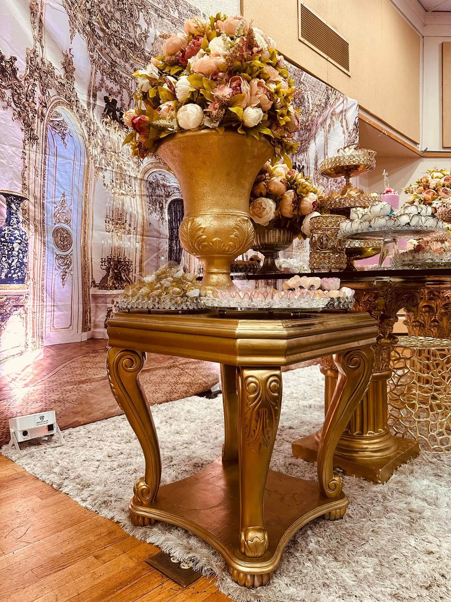 A gold table with a vase of flowers on top of it.
