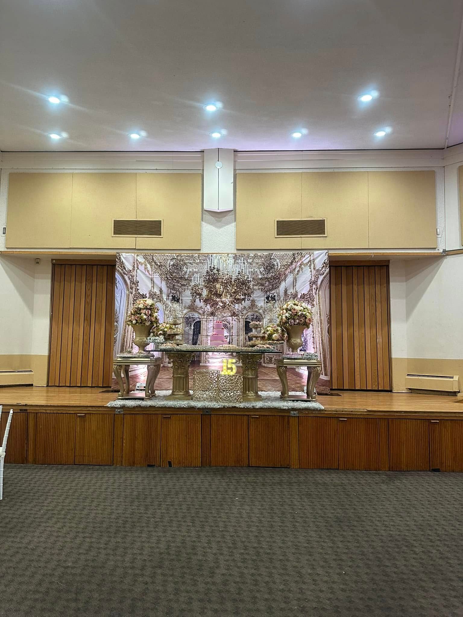 A large room with a stage and tables in it.