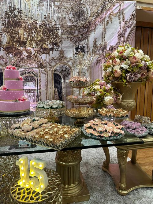 A table with a cake , cookies , and flowers on it.