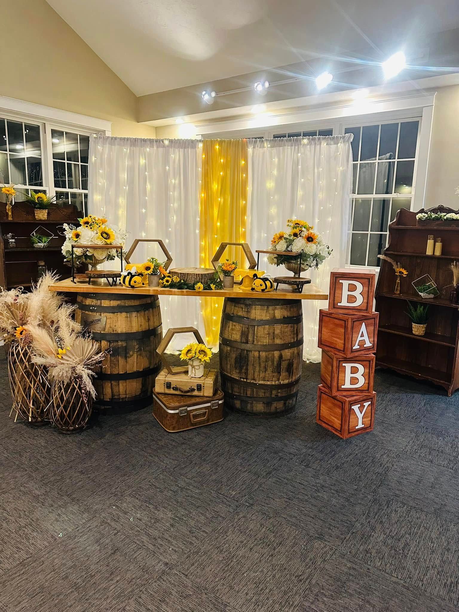A room decorated for a baby shower with barrels , baskets , boxes and flowers.
