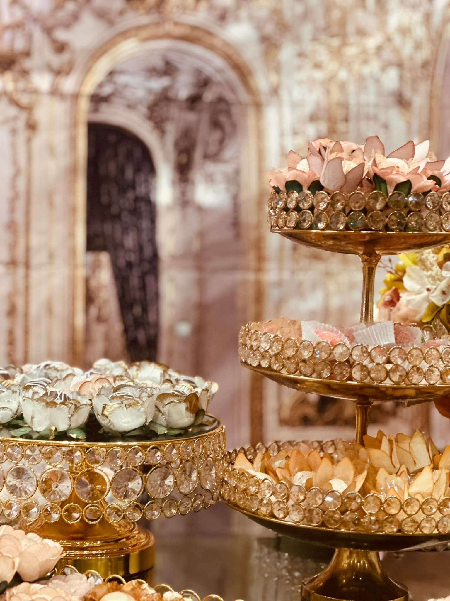 A table topped with three tier trays filled with cupcakes and flowers.