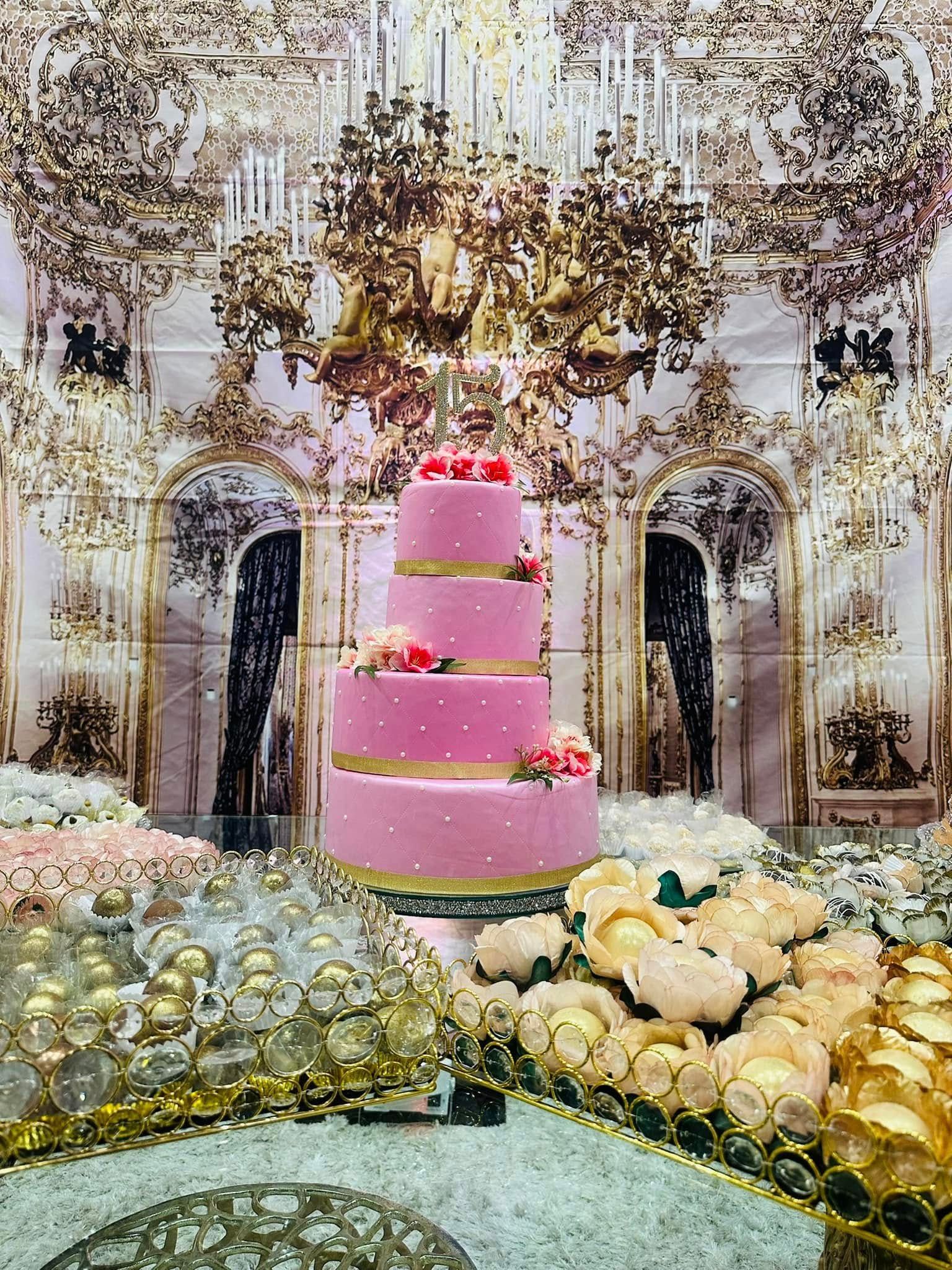 A pink wedding cake is sitting on top of a glass table.