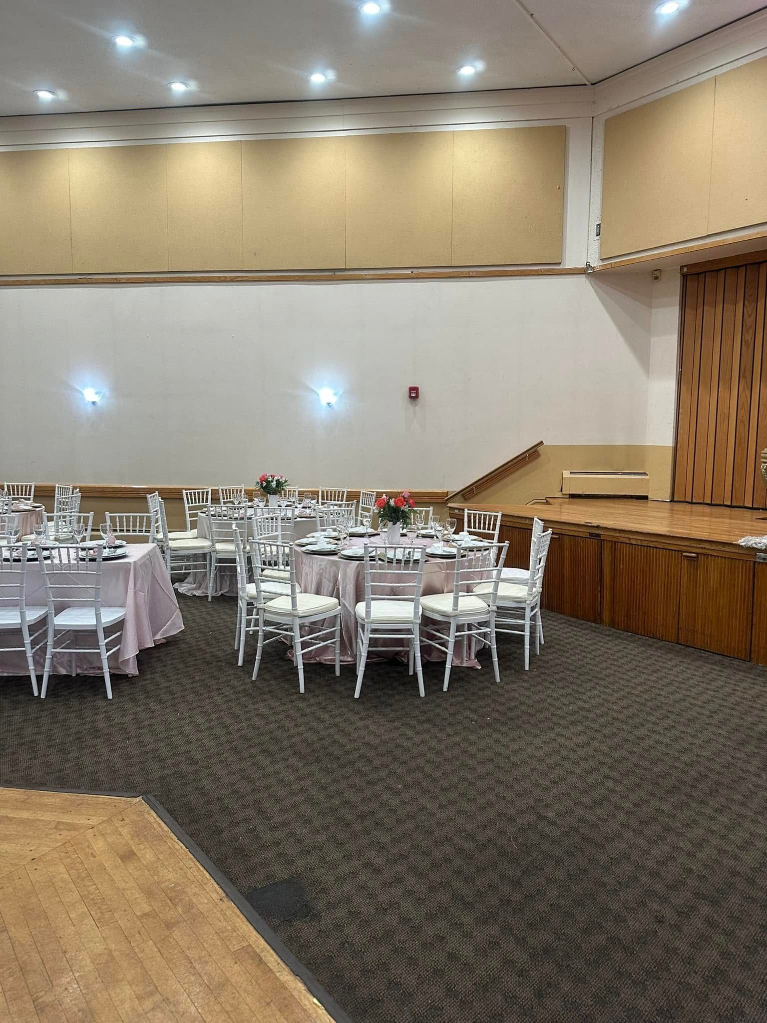A large room with tables and chairs set up for a wedding reception.