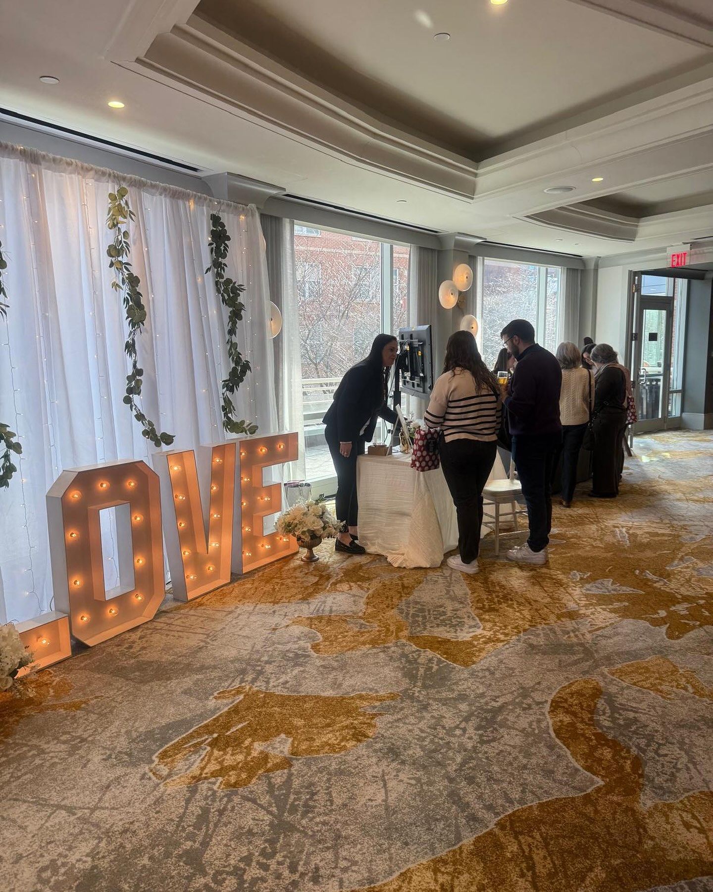 A group of people are standing around a table in a room with a sign that says `` love ''.