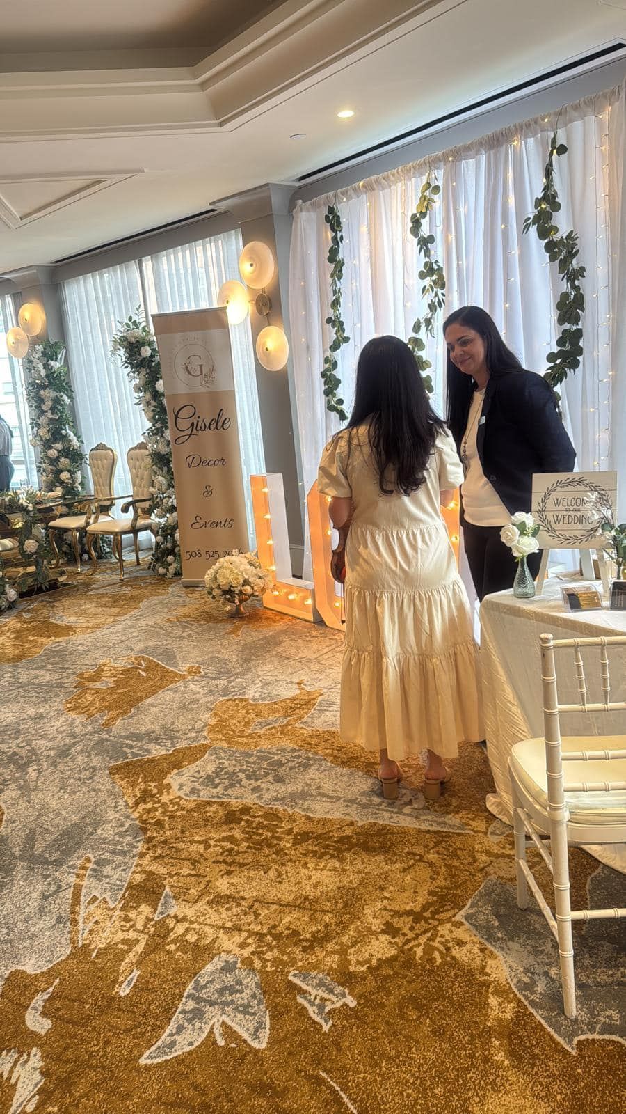 Two women are standing in a room talking to each other.