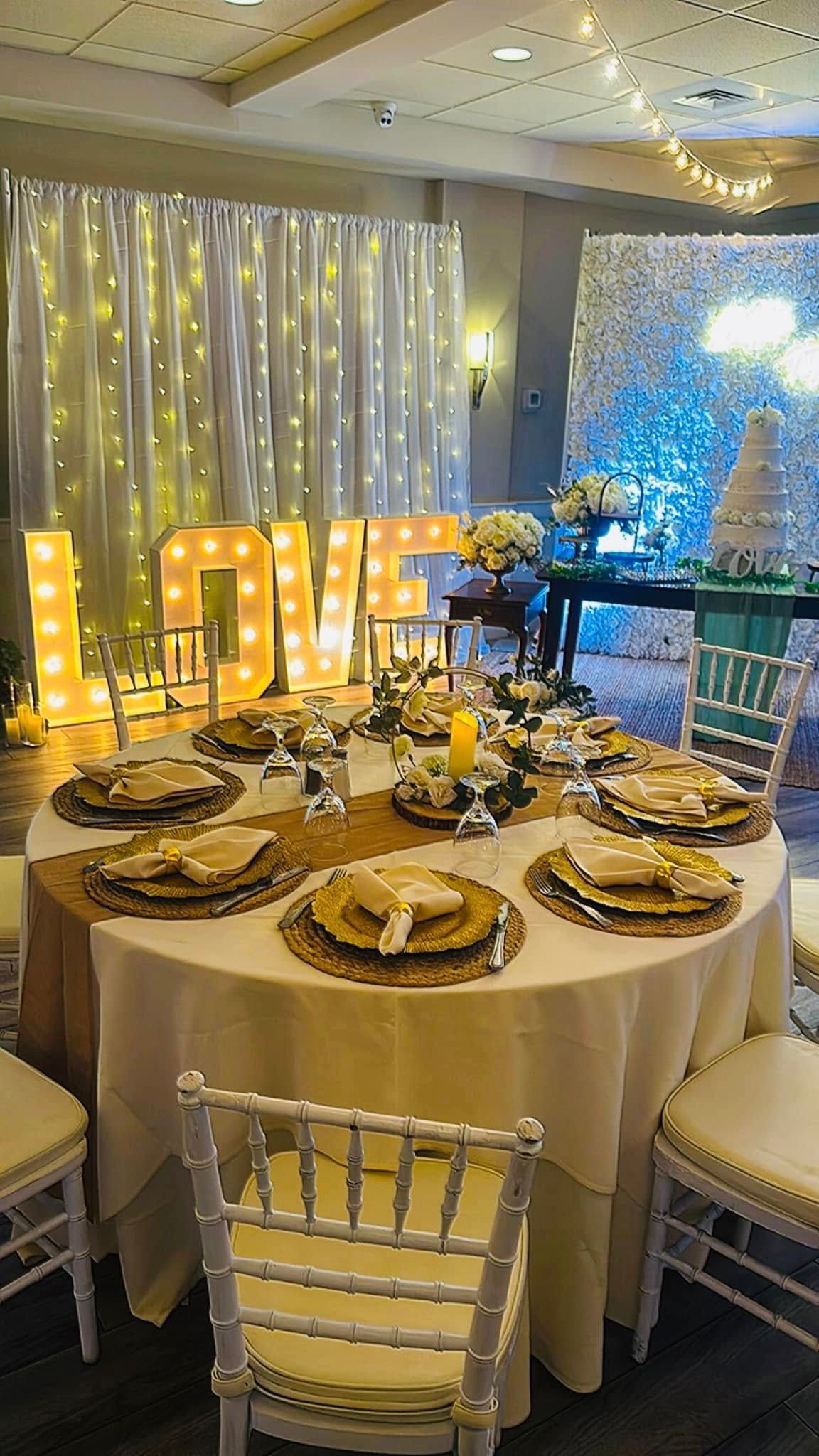 A table set for a wedding reception with a love sign in the background.