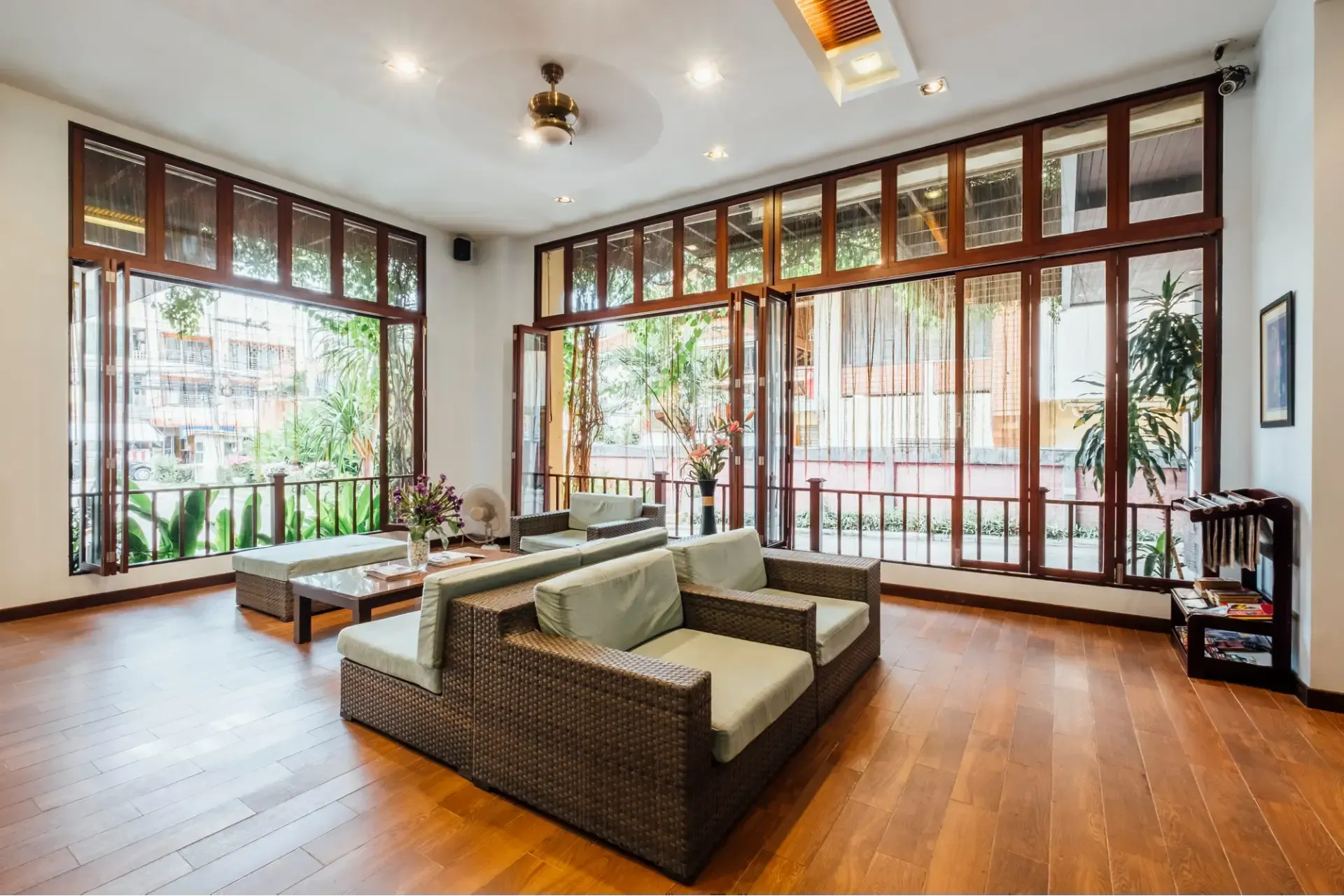 Bright-+modern+seating+area+featuring+rattan+sofas-+large+windows-+and+potted+plants-+creating+an+inviting-+natural+atmosphere