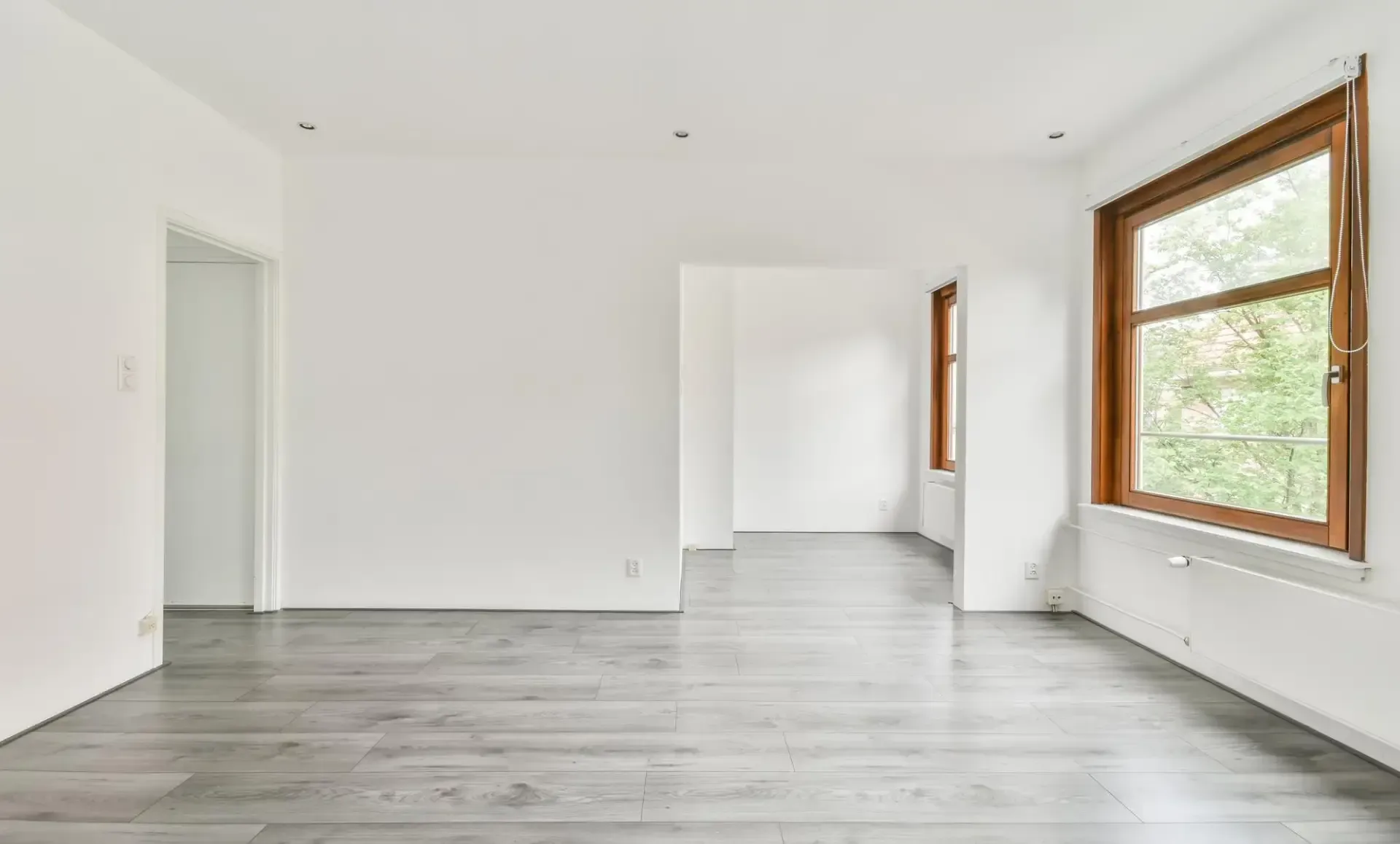 Bright-+spacious+room+with+light+gray+flooring-+white+walls-+and+large+windows-+creating+an+airy+and+inviting+atmosphere