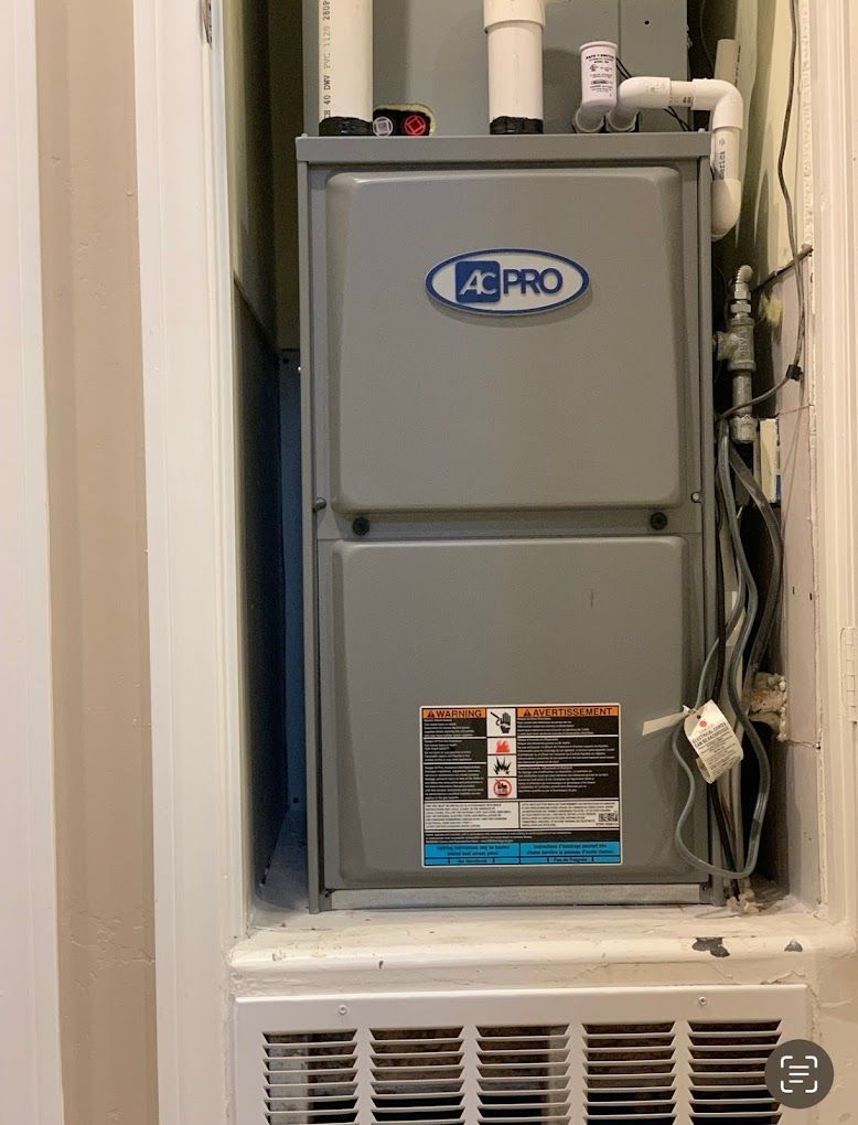 A gray ac pro air conditioner is sitting on top of a white wall.