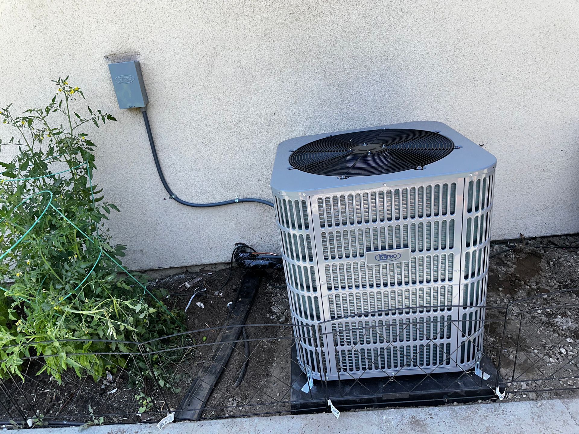An air conditioner is sitting on the ground next to a wall.