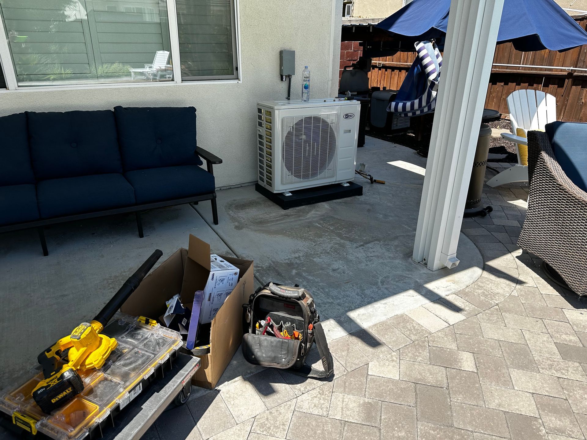 A patio with a couch , chairs , and a box of tools.