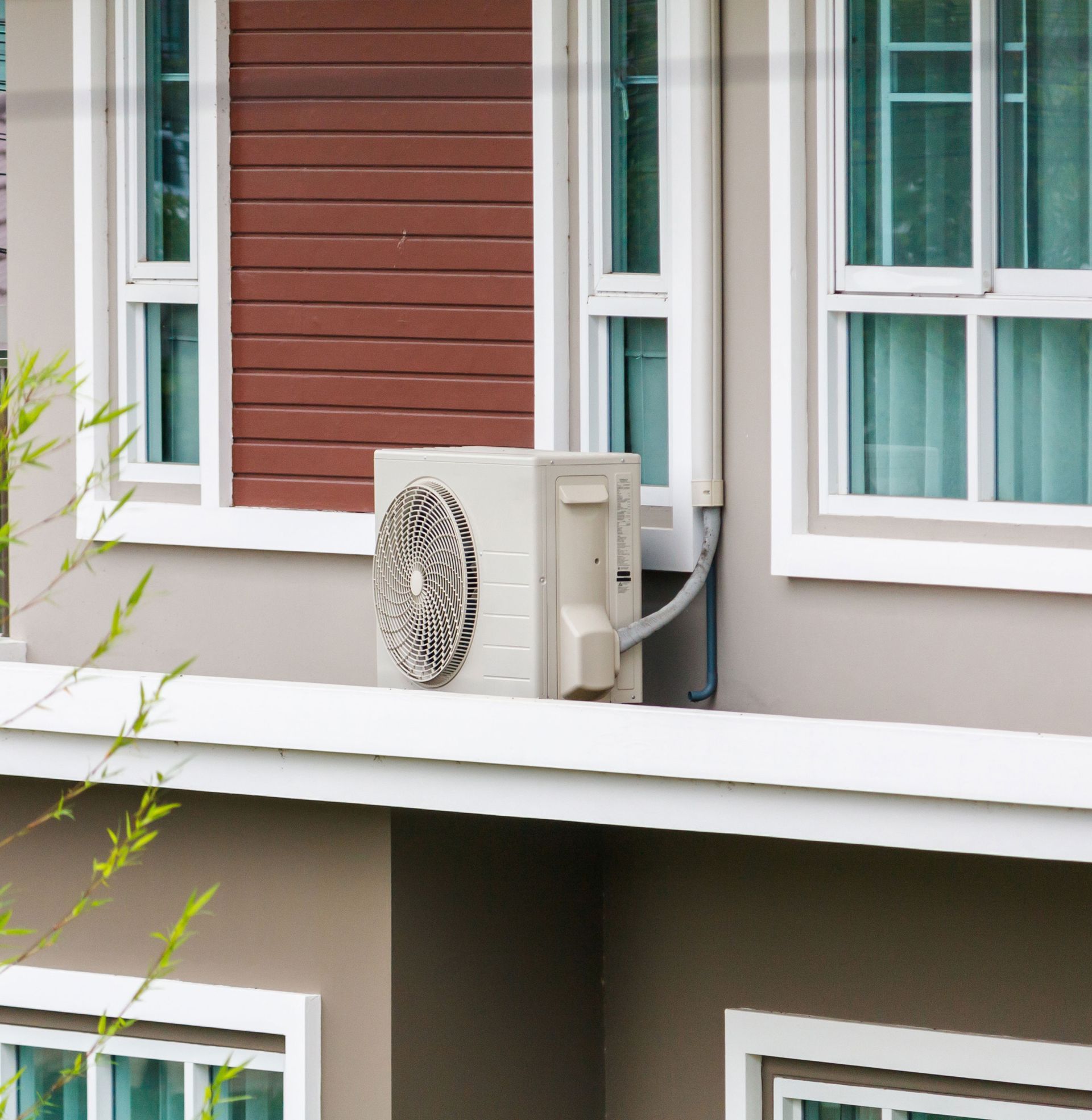 An air conditioner is mounted on the side of a house