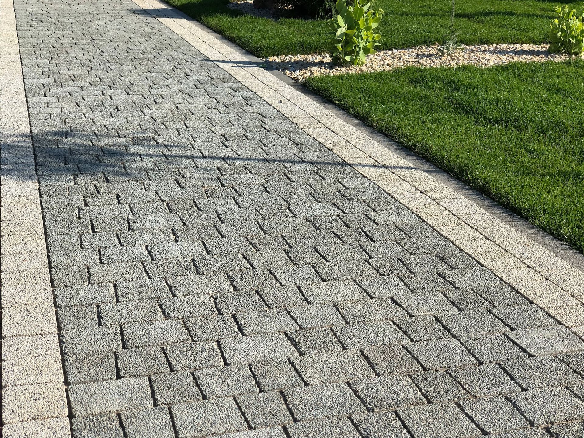 Stone path with a border, beside green grass.