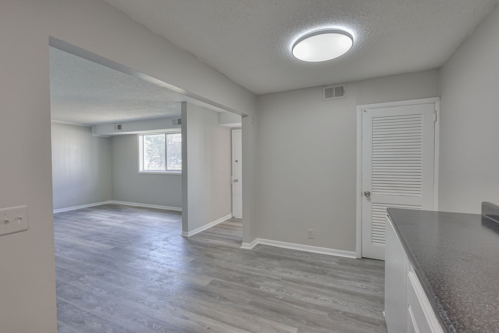 Photo showing a kitchen entrance area, with the living room, and front door entrance in the background