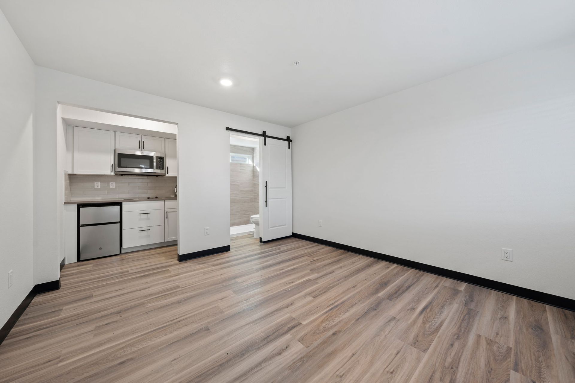 A living room with a sliding barn door leading to a kitchen.