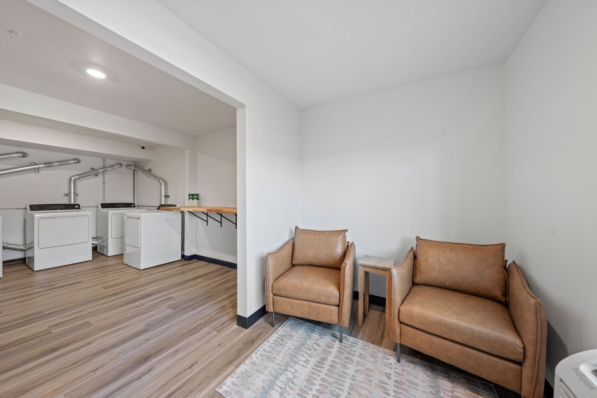 A living room with two chairs and a table in a laundry room.