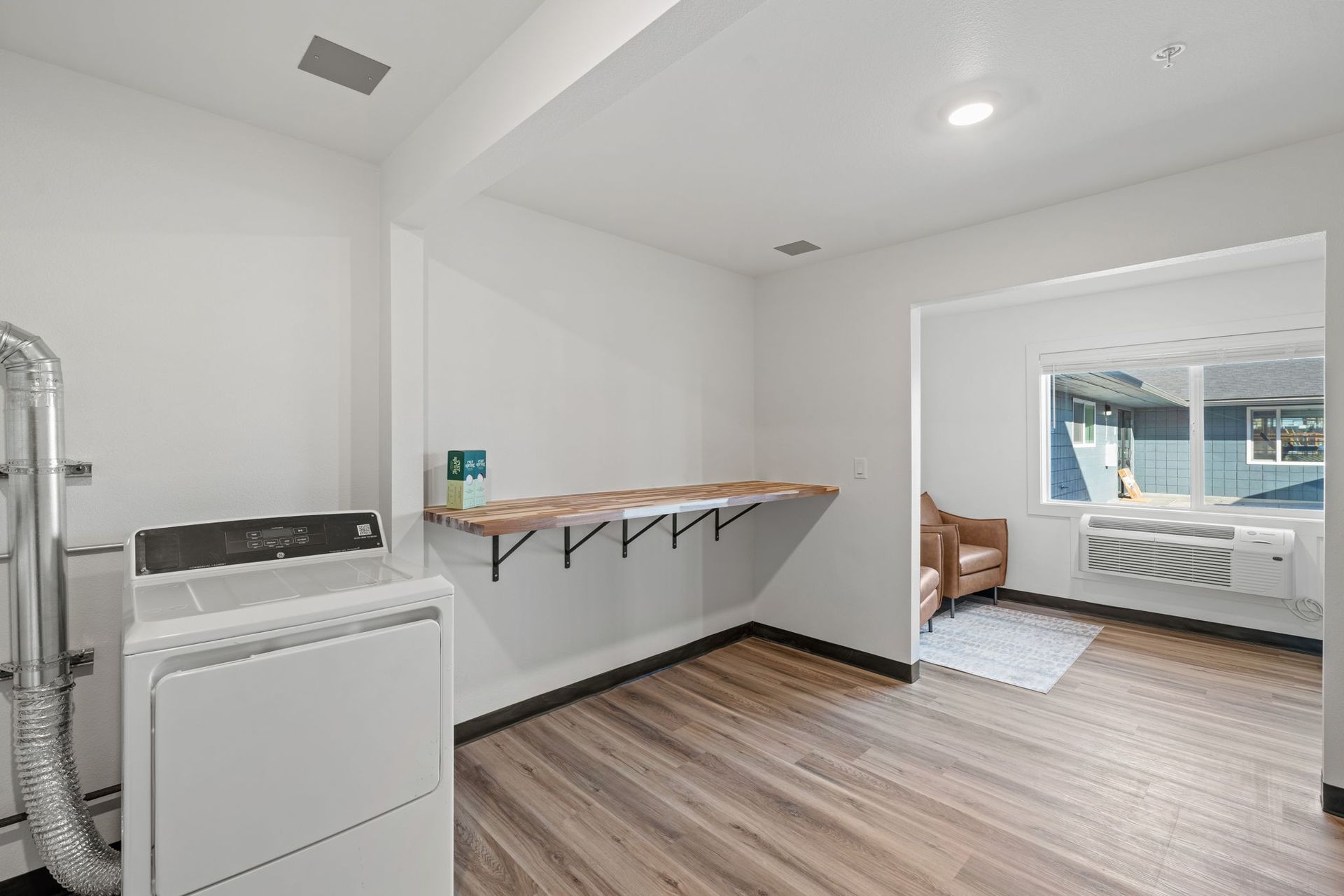 A laundry room with a washer and dryer and a wooden floor.
