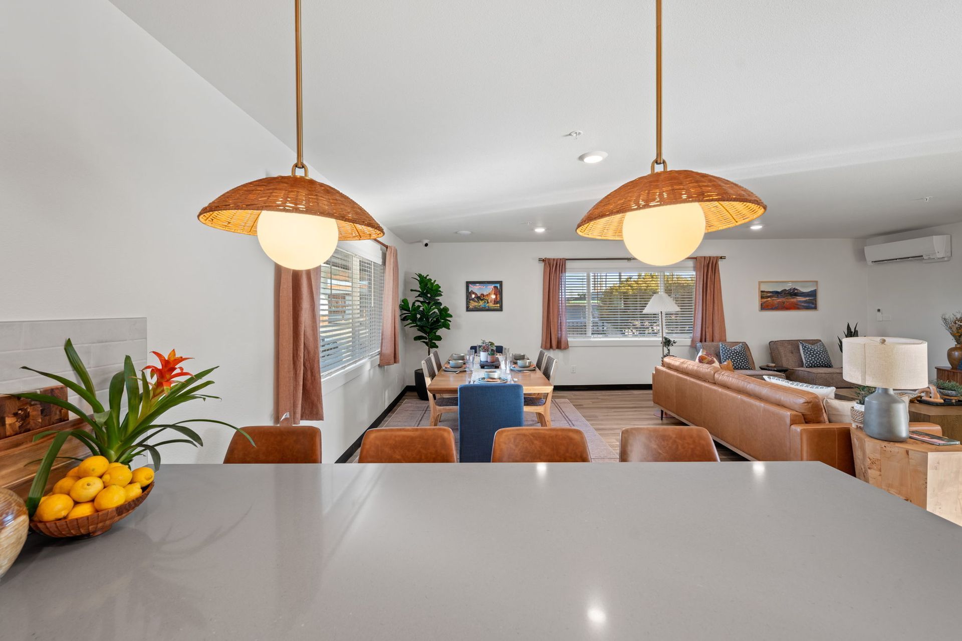 A living room with a couch , table , chairs and a bowl of fruit on the counter.