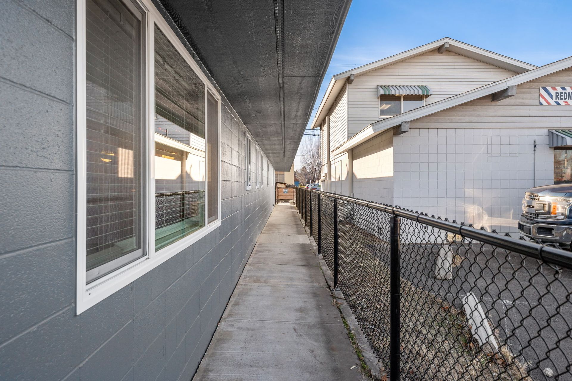 A long hallway between two buildings with a chain link fence.