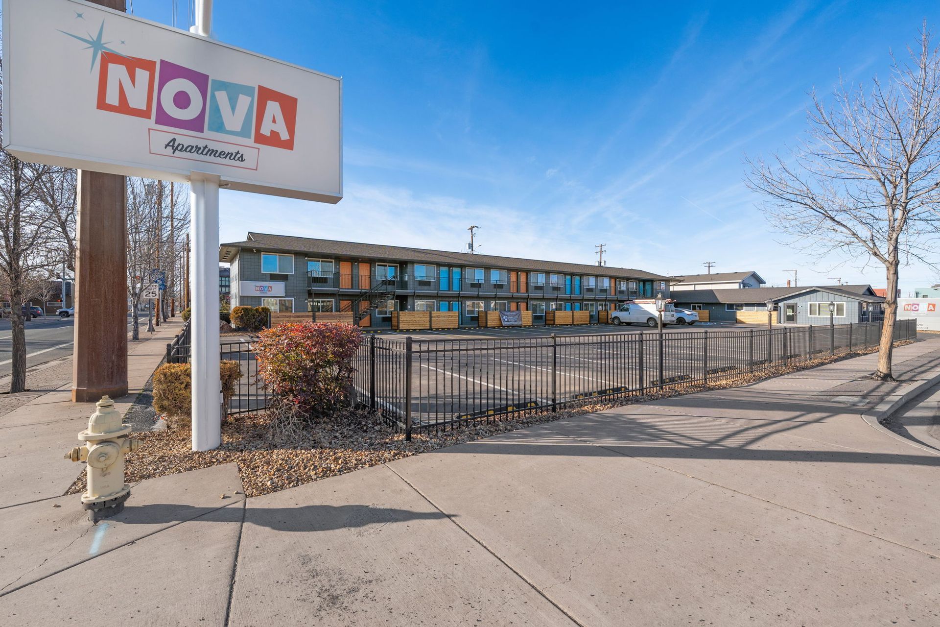A sign for nova apartments is sitting on the sidewalk next to a fire hydrant.