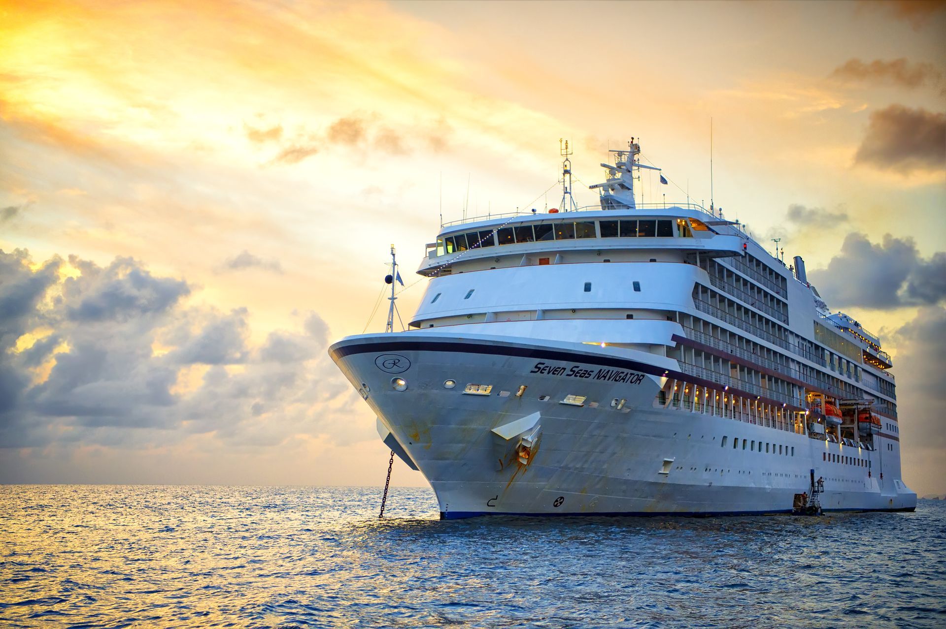 A large cruise ship is floating on top of a body of water at sunset.