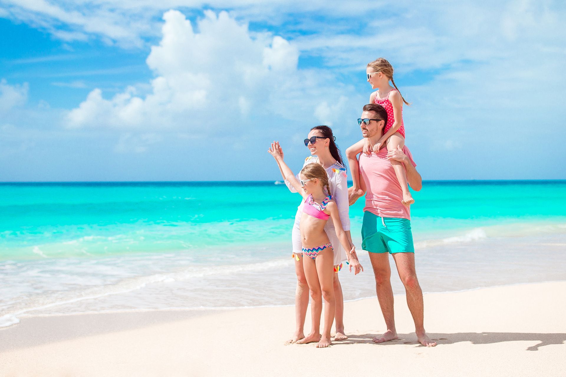 A family is standing on a beach looking at the ocean.