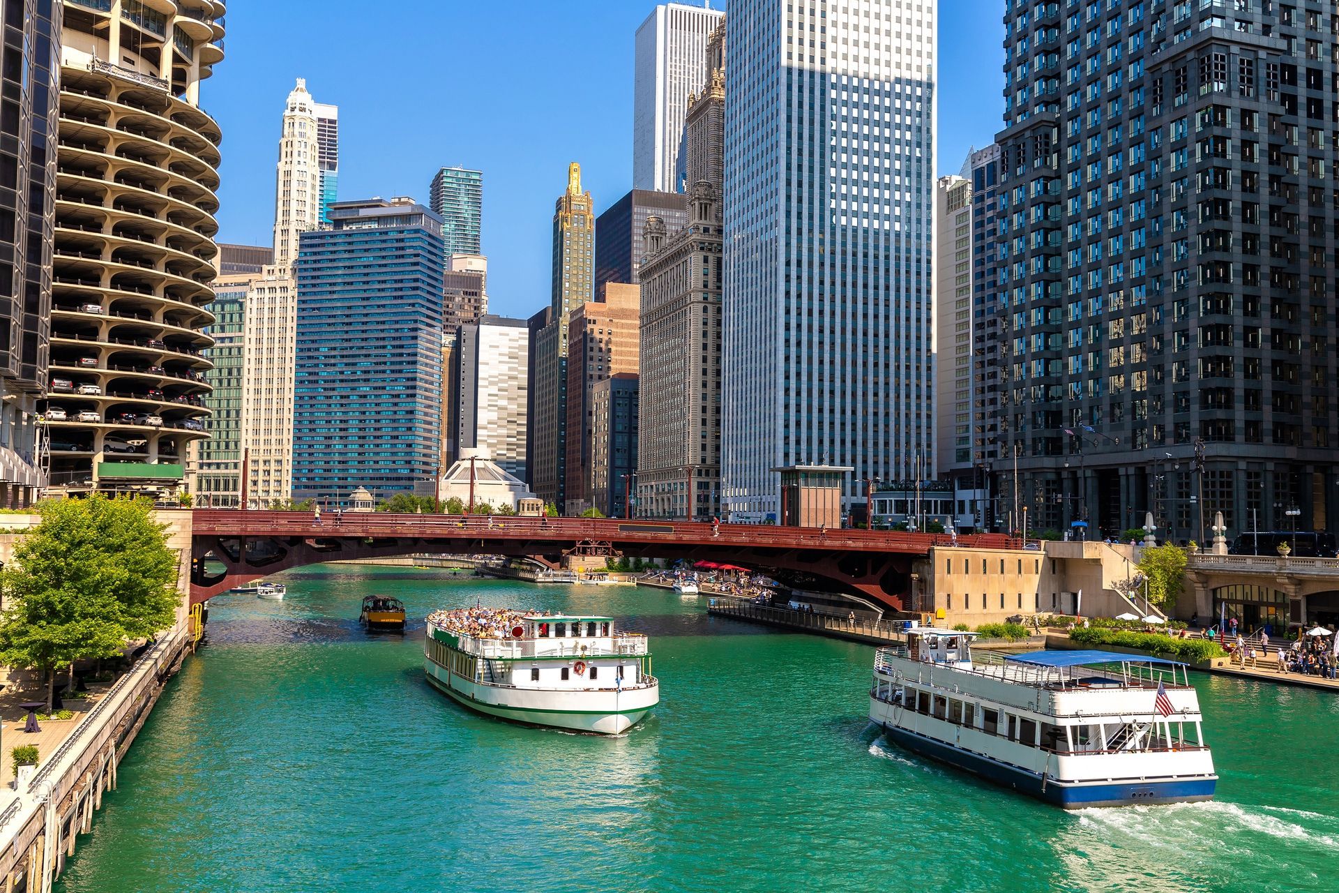 A couple of boats are floating down a river in a city.