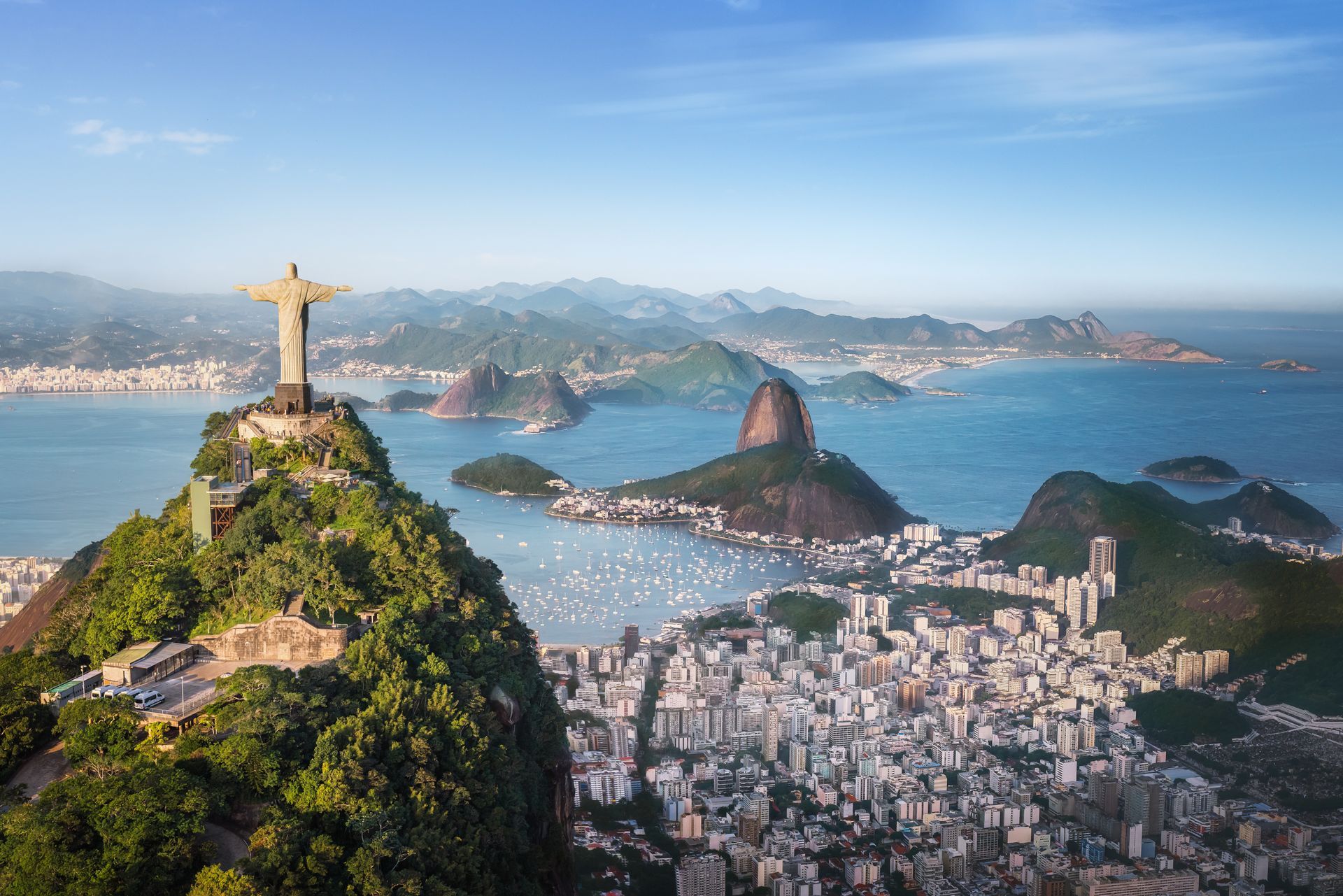 A statue of jesus is sitting on top of a hill overlooking a city.