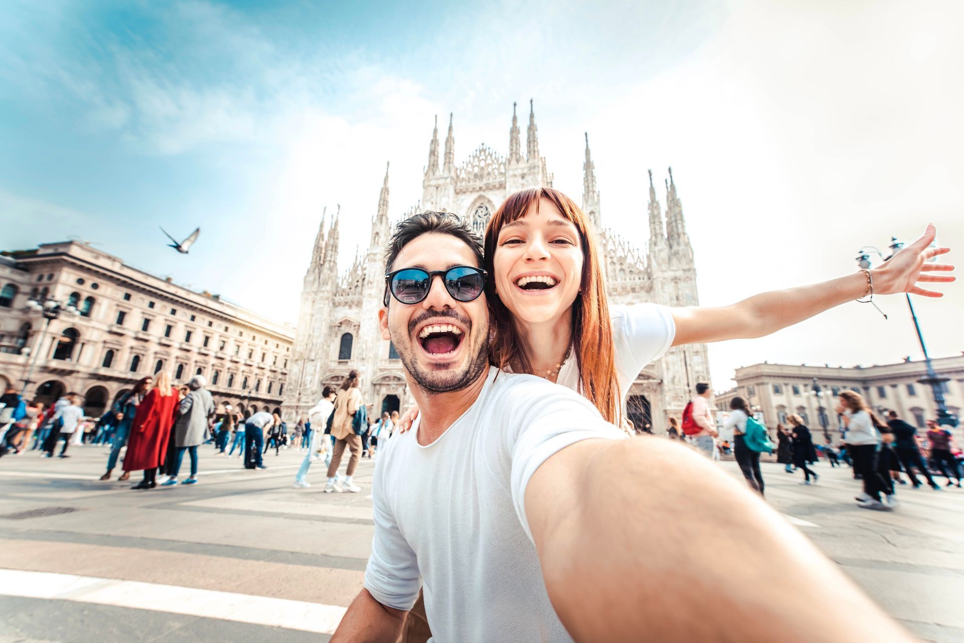 A man and a woman are taking a selfie in front of a cathedral.