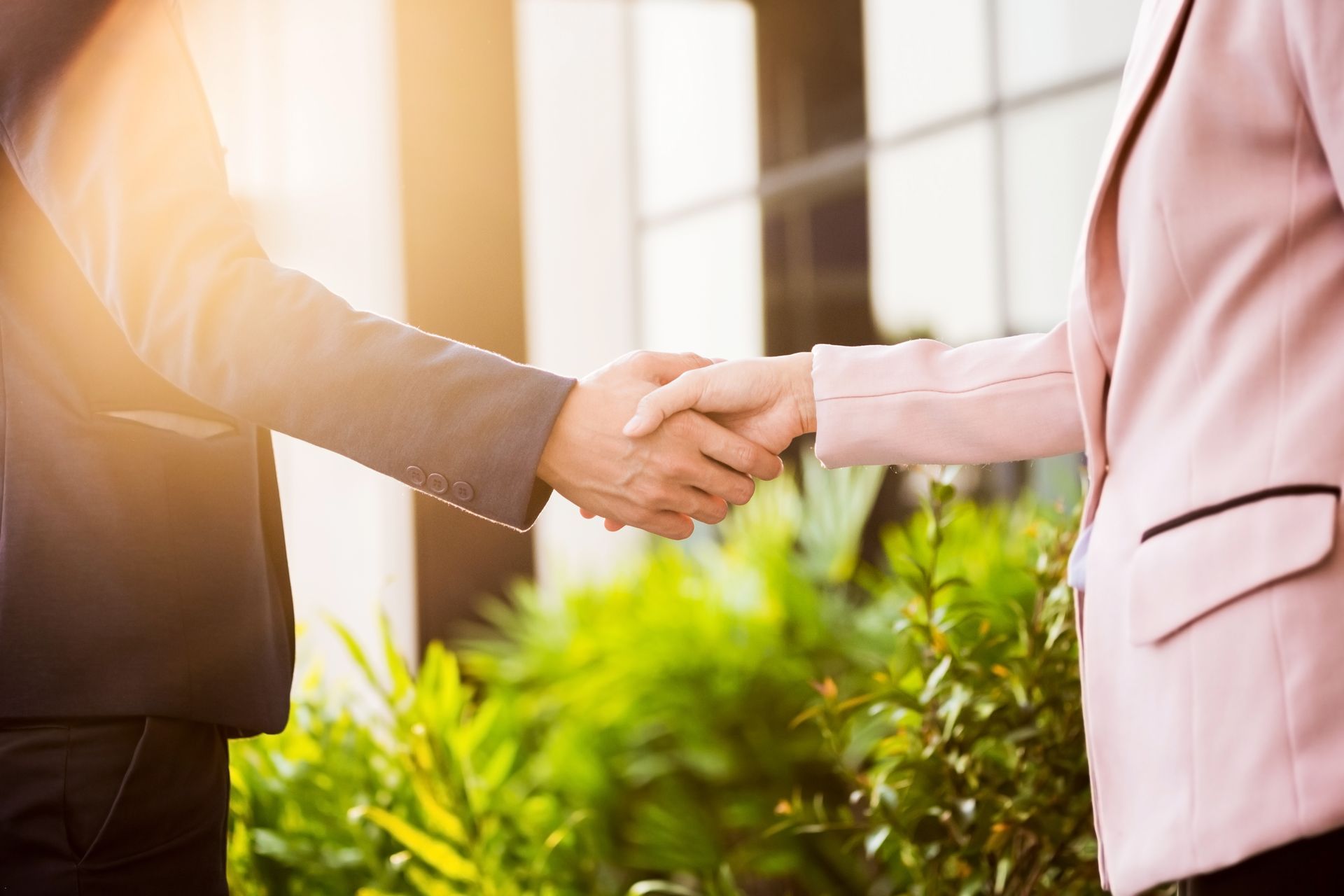 A man and a woman are shaking hands in front of a building.