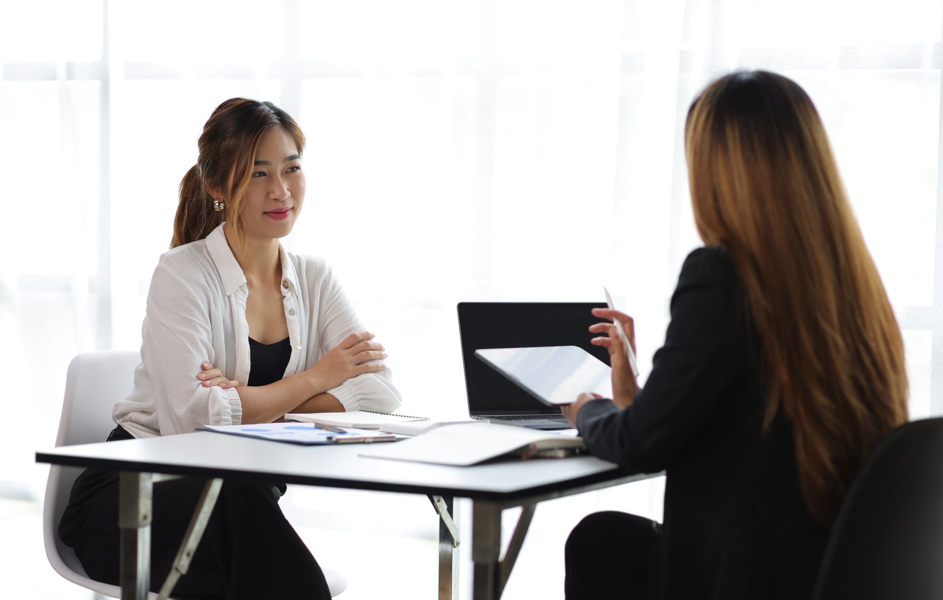 Two women are sitting at a table having a conversation.