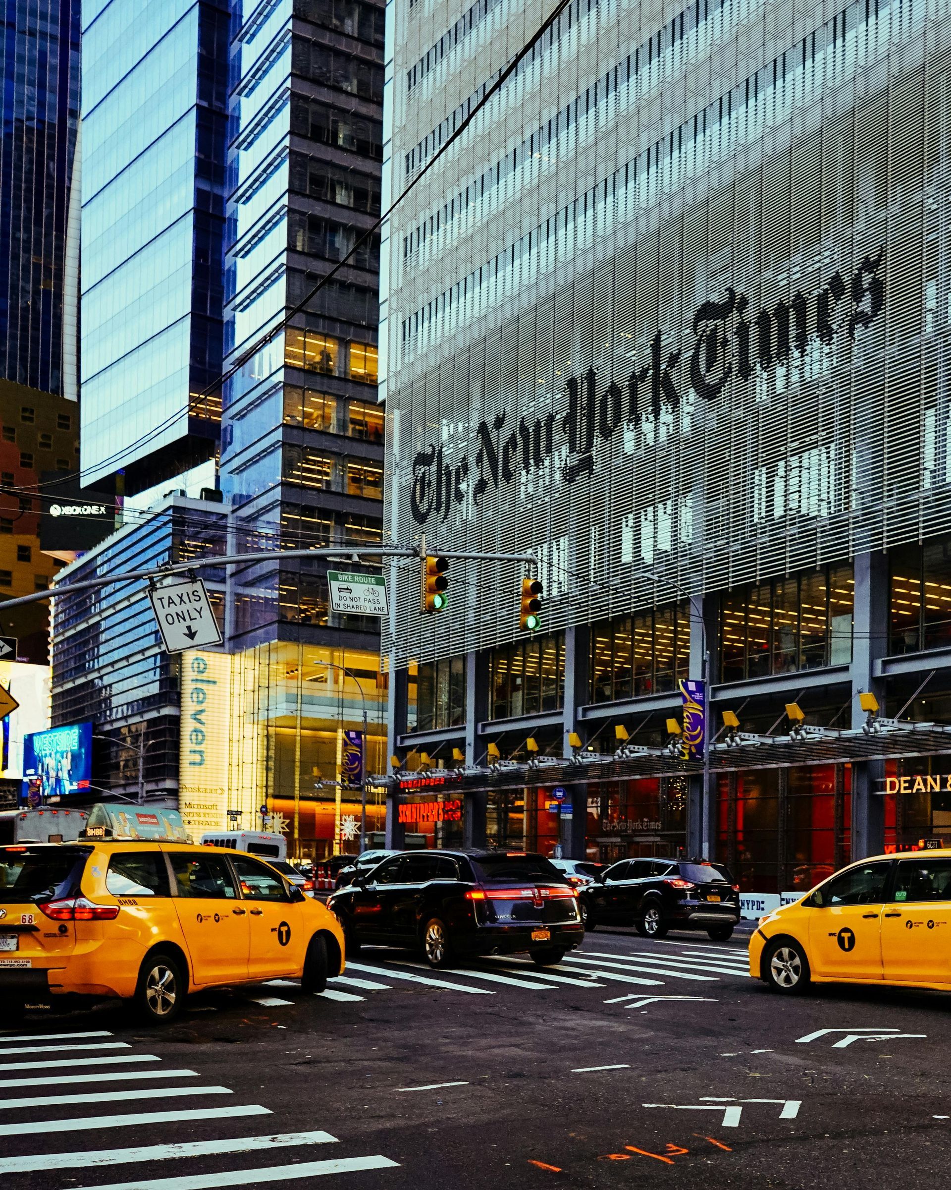 Taxis are driving down a city street in front of the new york times building