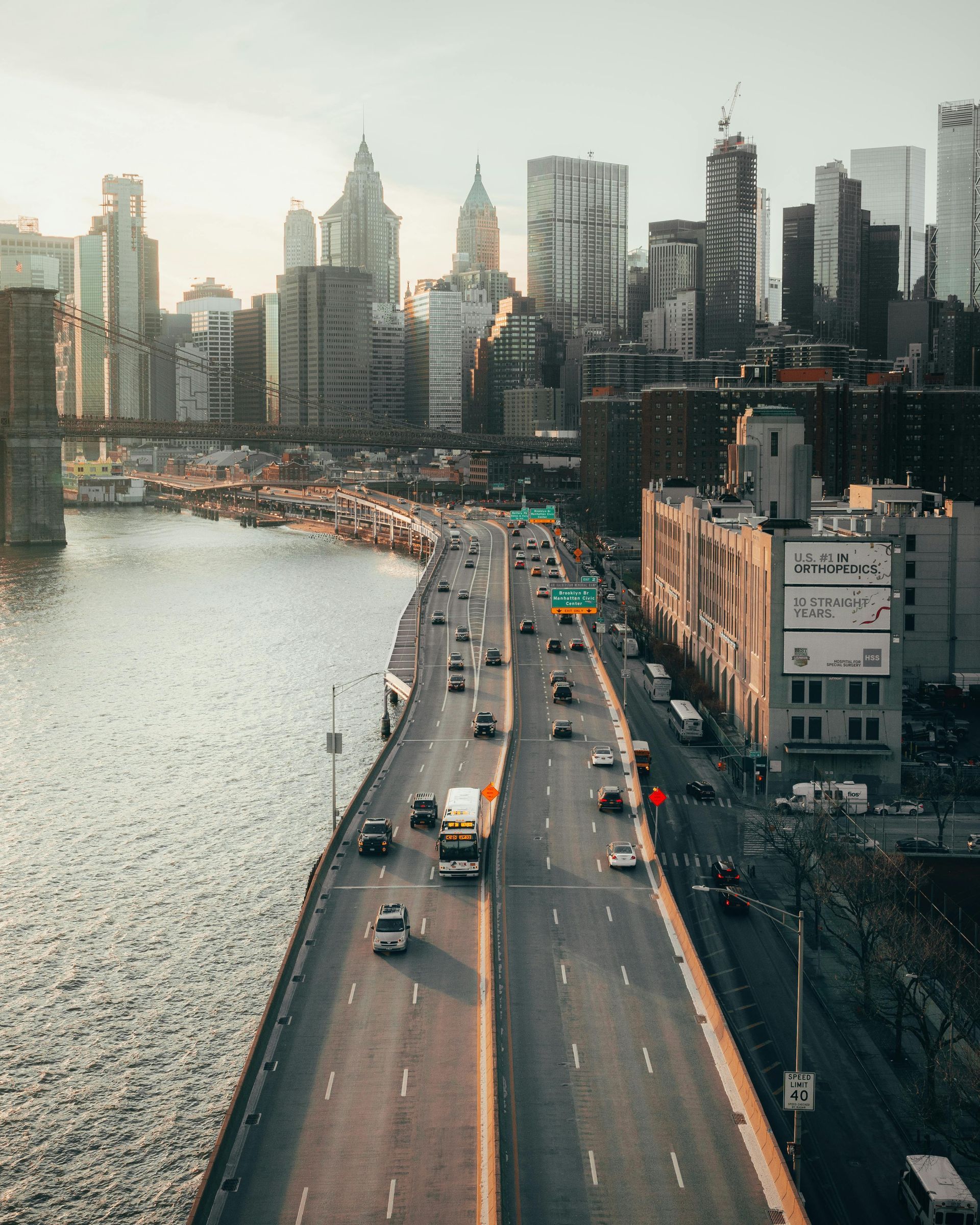 Overhead view of a highway in NYC, cars driving with skyline buildings in the background.