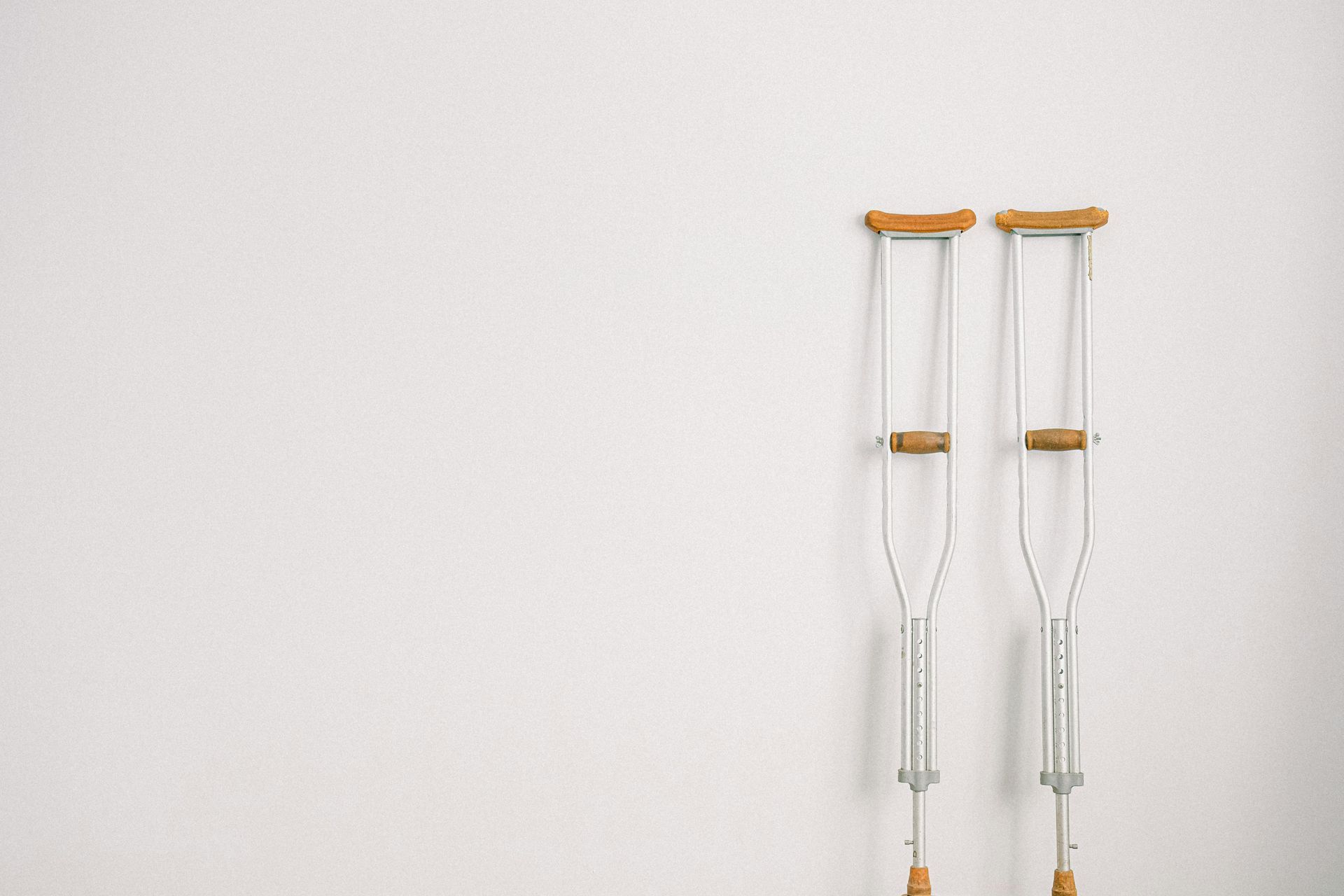 Pair of crutches leaning against a white wall.