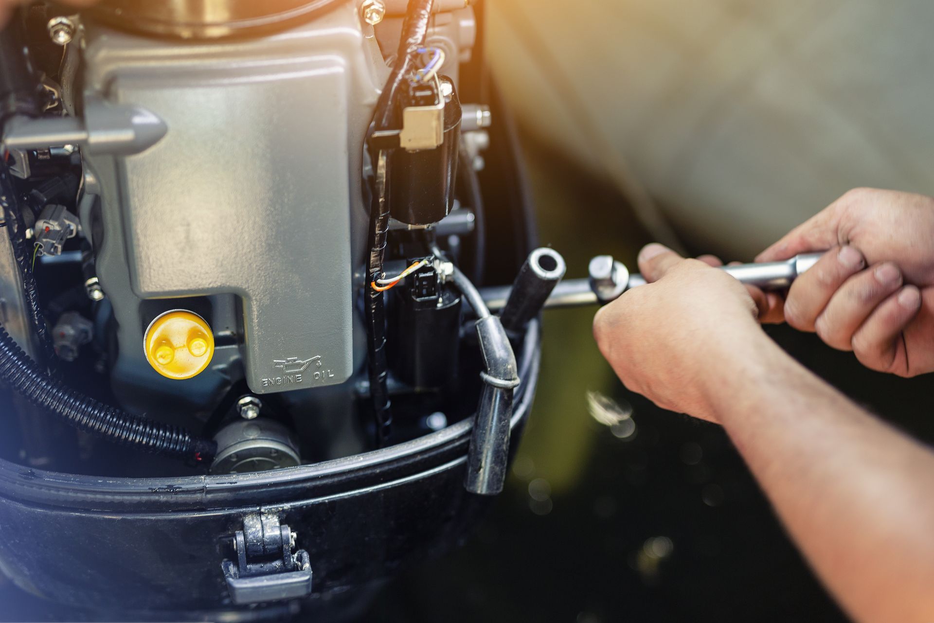 A pair of hands using a socket wrench to work on a boat's outboard motor.