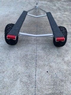 A boat trailer with wheels is sitting on a concrete surface.