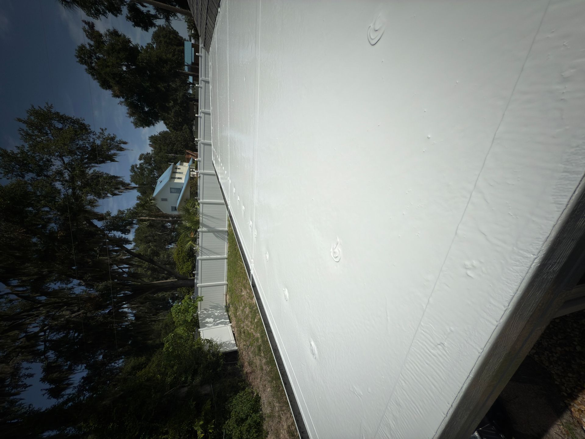 A white roof with a fence and trees in the background