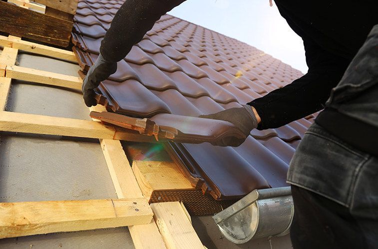 A man is installing a tile roof on a house.