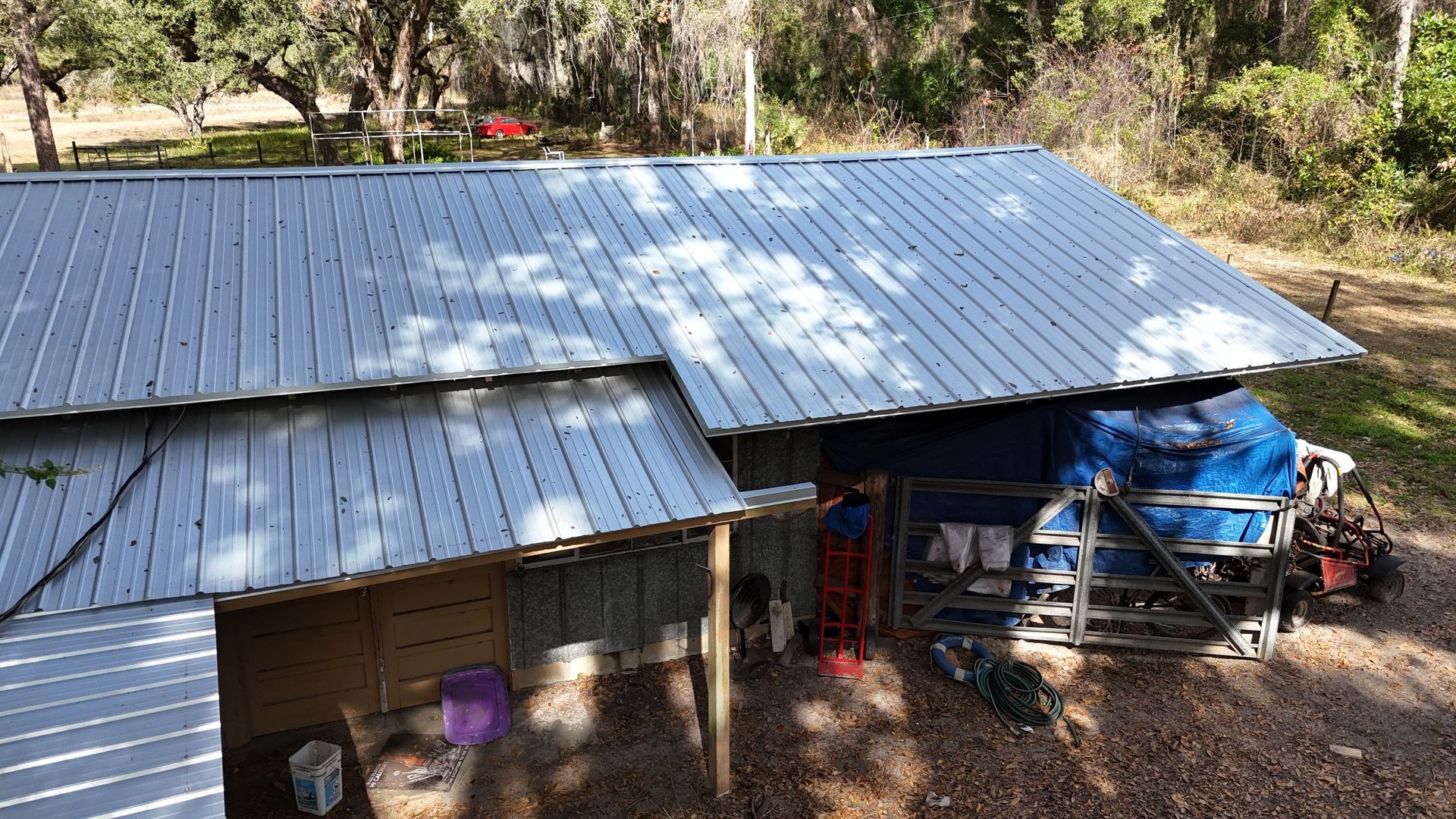 An aerial view of a barn with a metal roof in the woods.